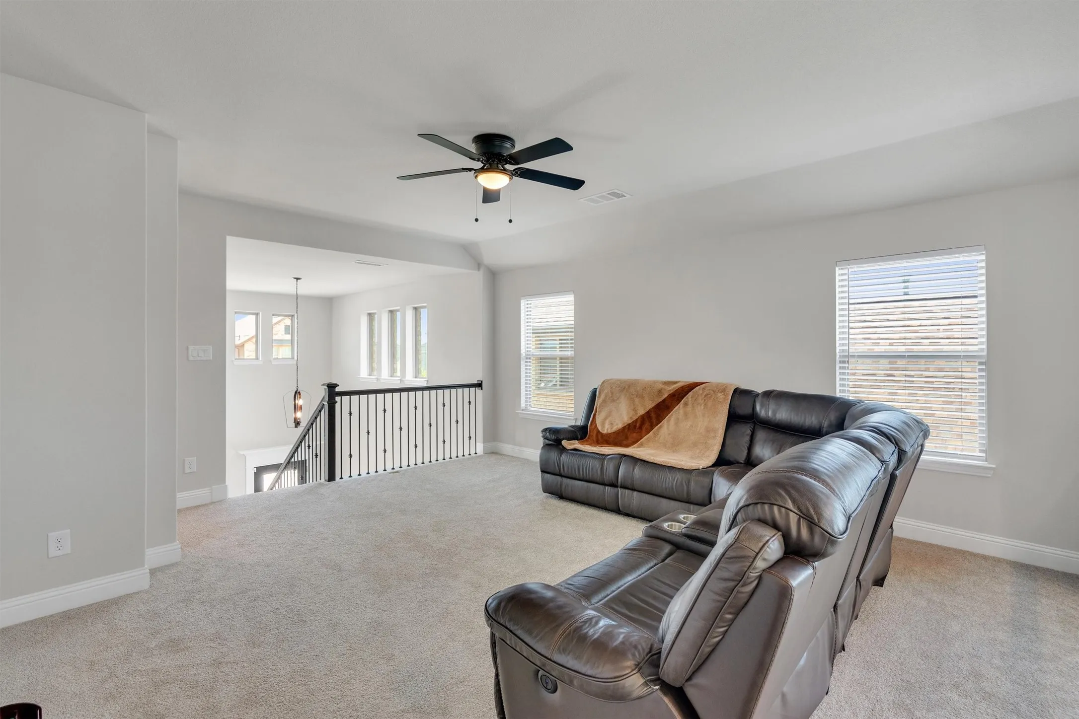 Spacious upstairs loft area featuring light gray carpeting and white baseboards
