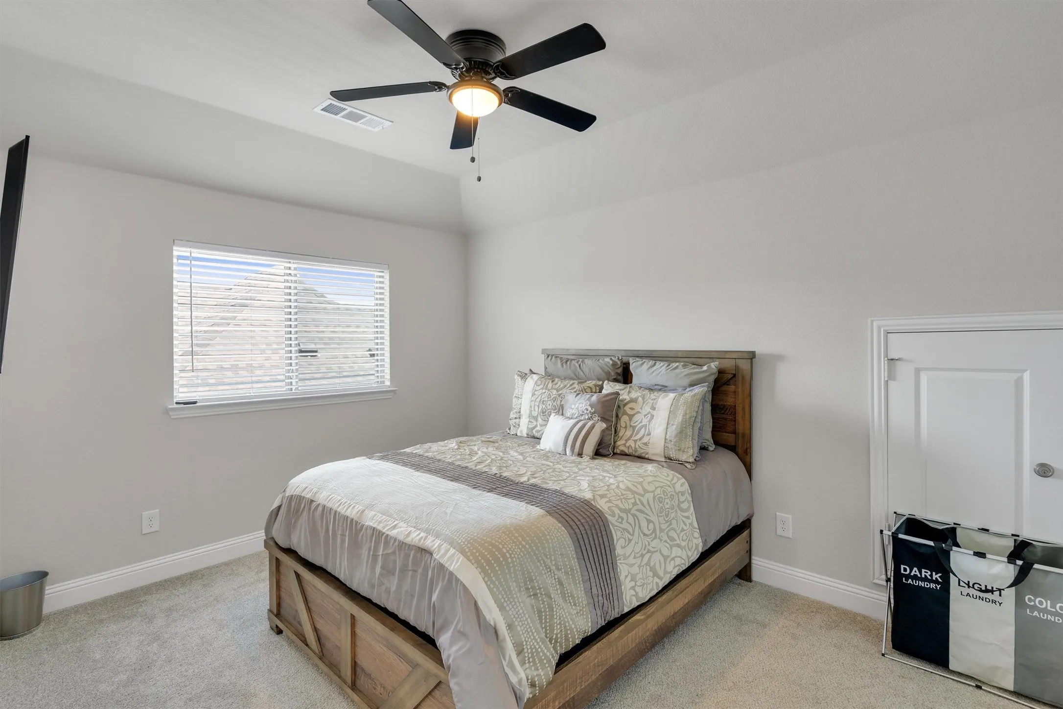 Carpeted room featuring a ceiling fan with integrated lighting, a window with horizontal blinds, a single door with a knob, and white baseboards