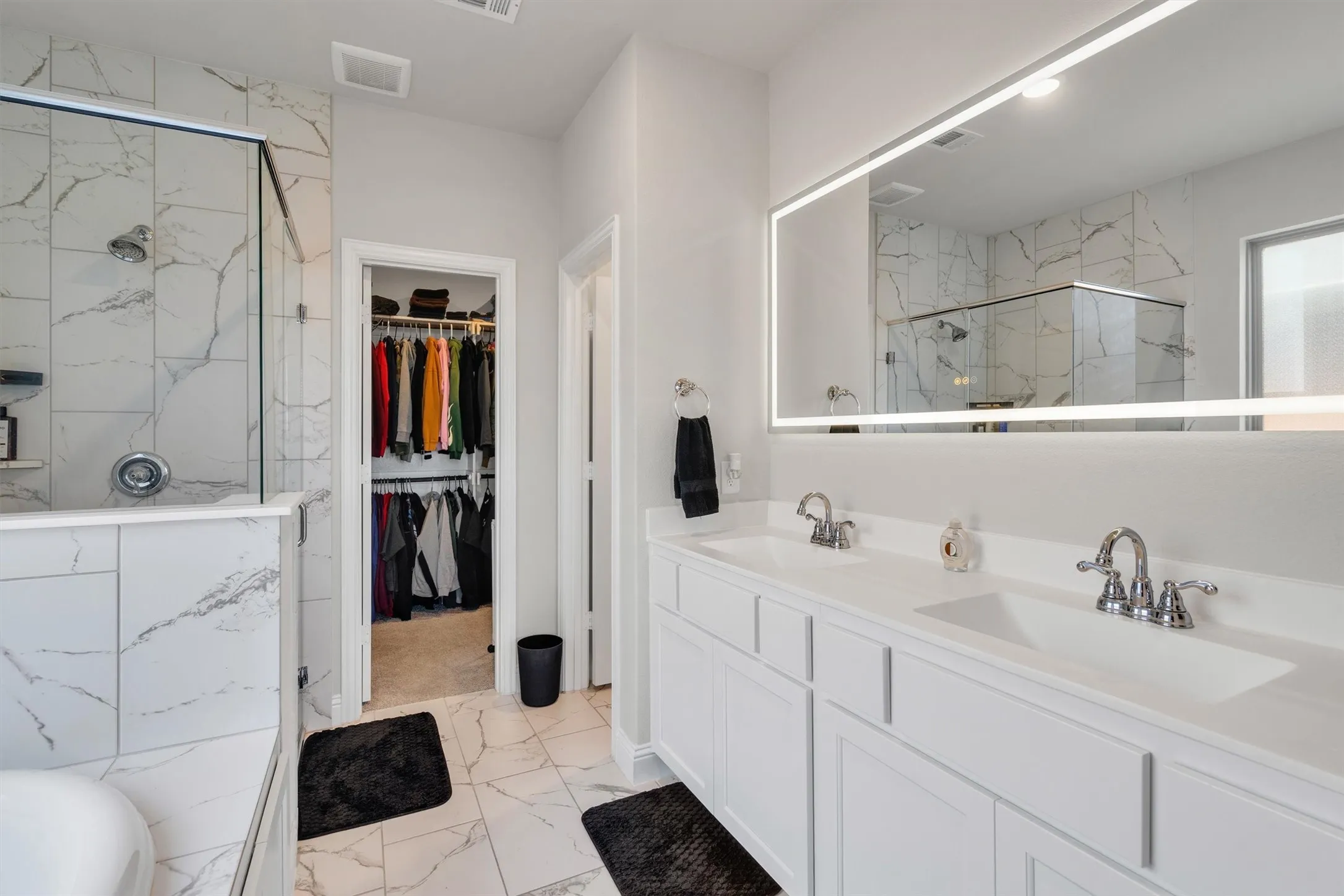 Bathroom featuring a dual vanity with white cabinetry, integrated sinks, and chrome fixtures