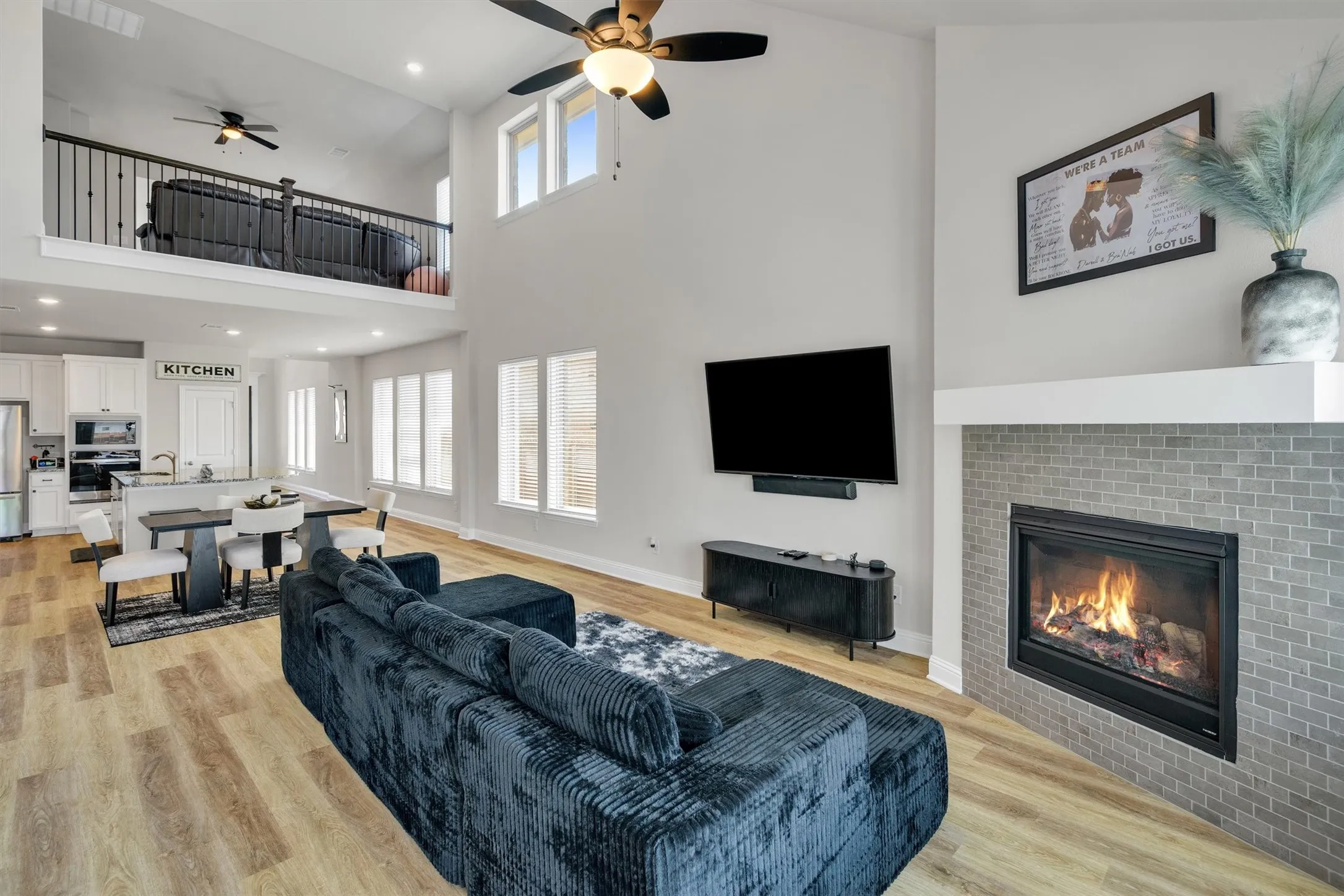 Spacious living area featuring high ceilings, light wood-finish flooring, and multiple windows