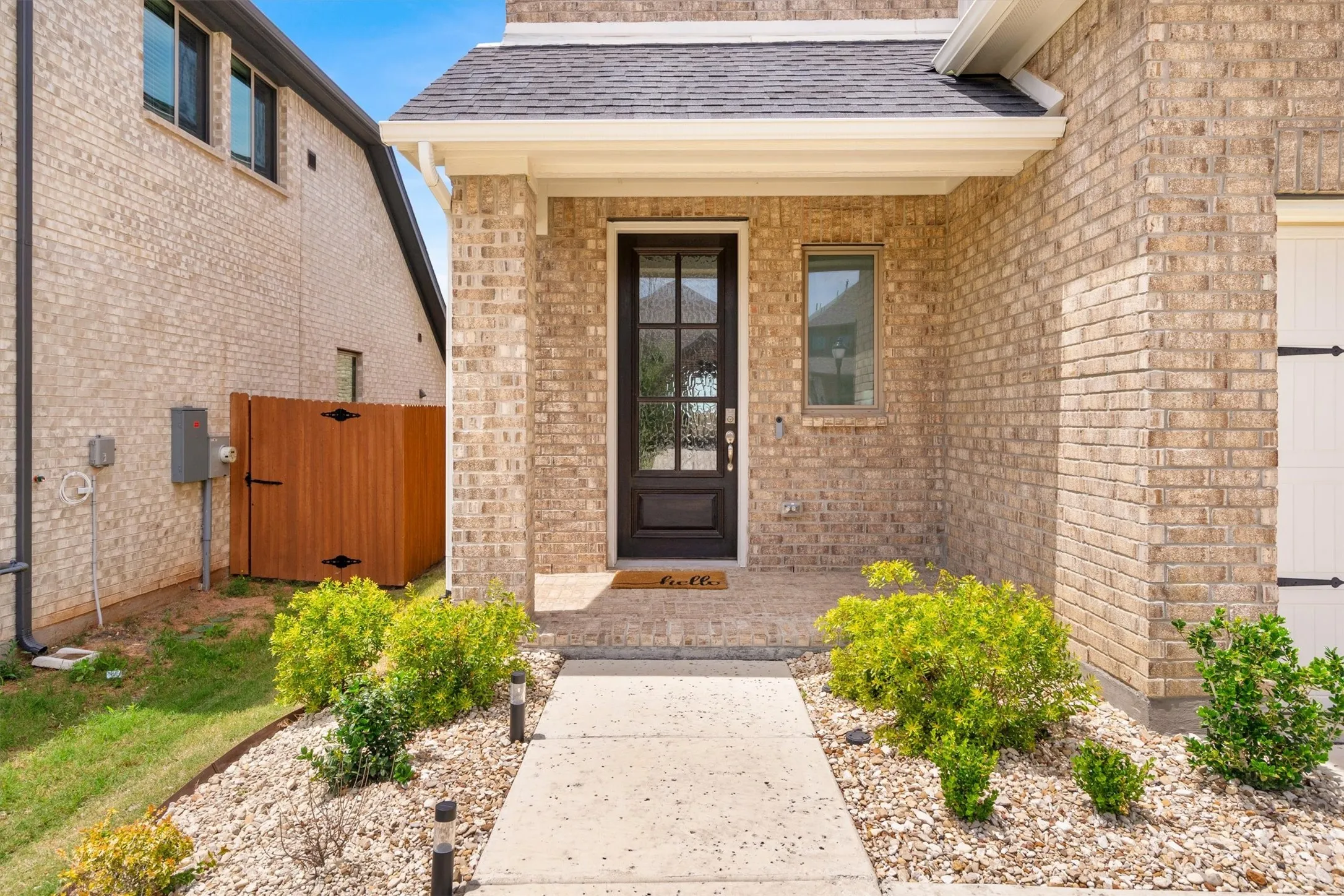 Brick exterior with a covered entry, dark paneled front door, and an architectural shingle roof