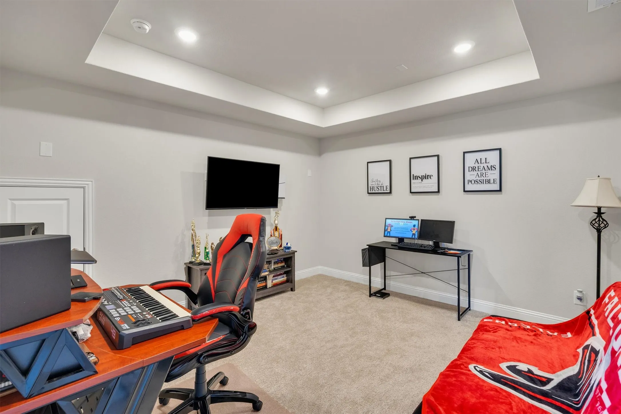Recessed lighting illuminates a tray ceiling and light-colored carpeting