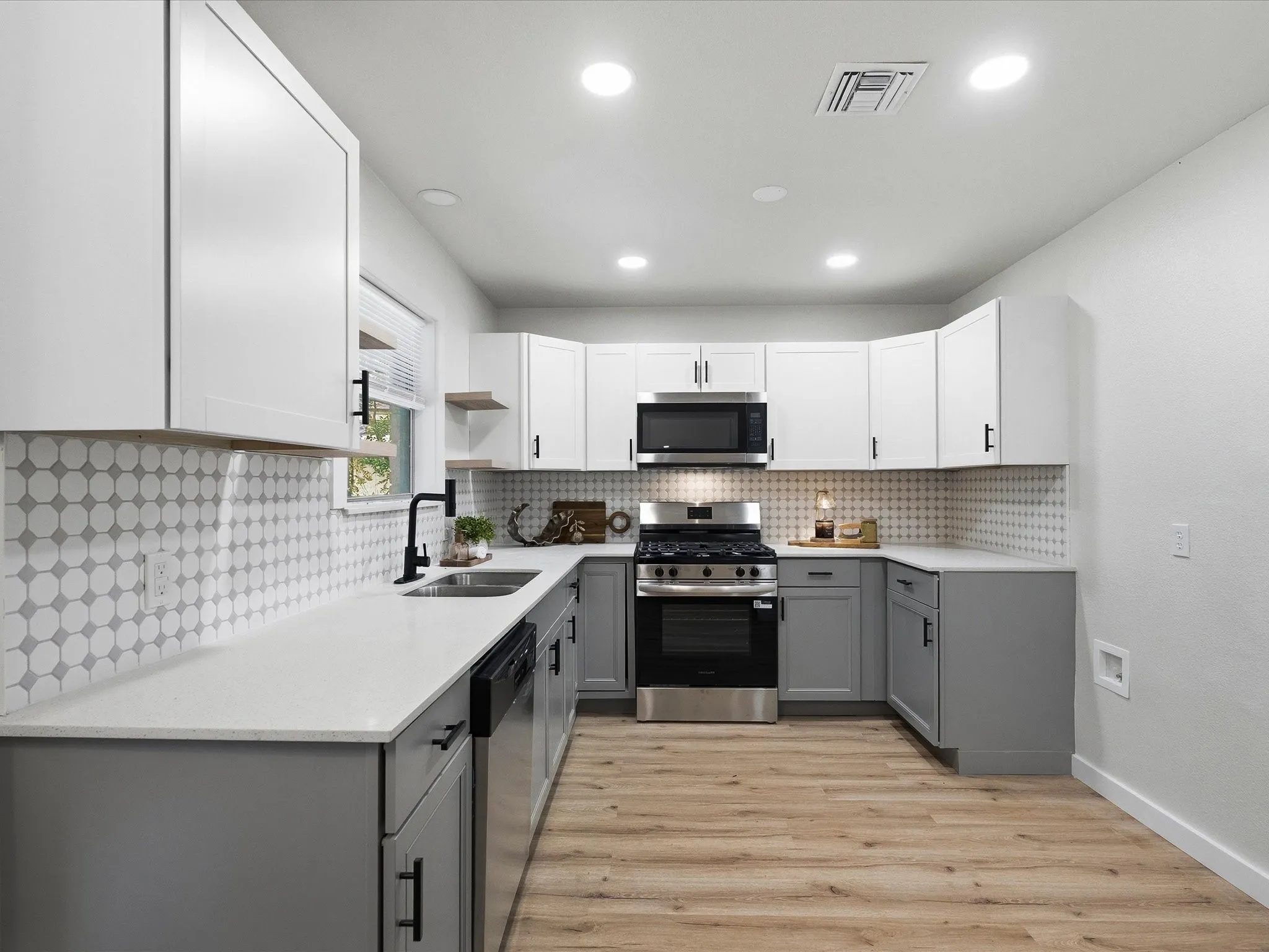 The kitchen features cute tile backsplash, floating shelves, updated cabinets, granite counters, ss appliances, new fixtures, new paint, updated lighting and more!