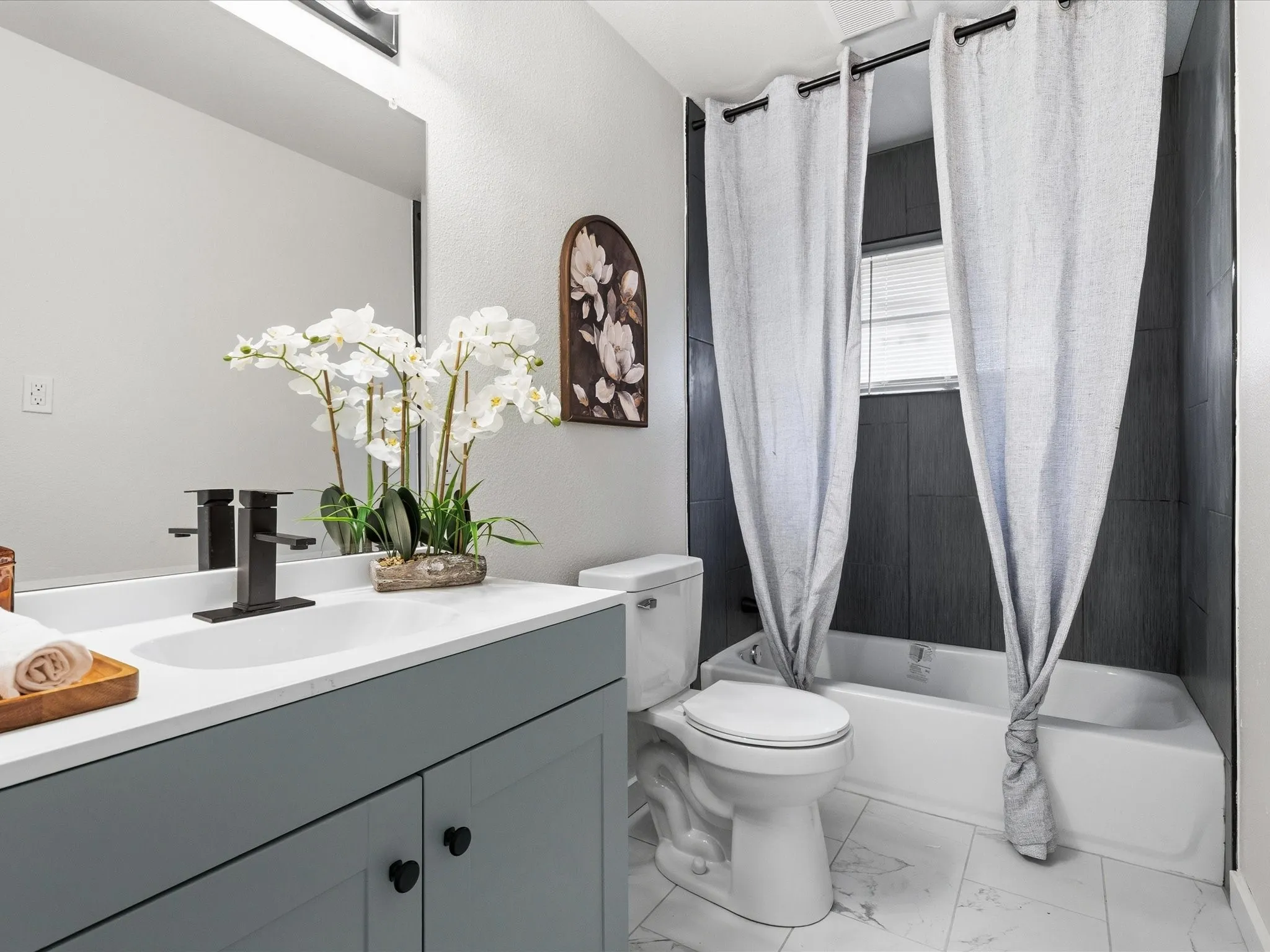 Guest bathroom is spacious and features a new vanity, tile shower, tile floors, updated paint, and updated fixtures.