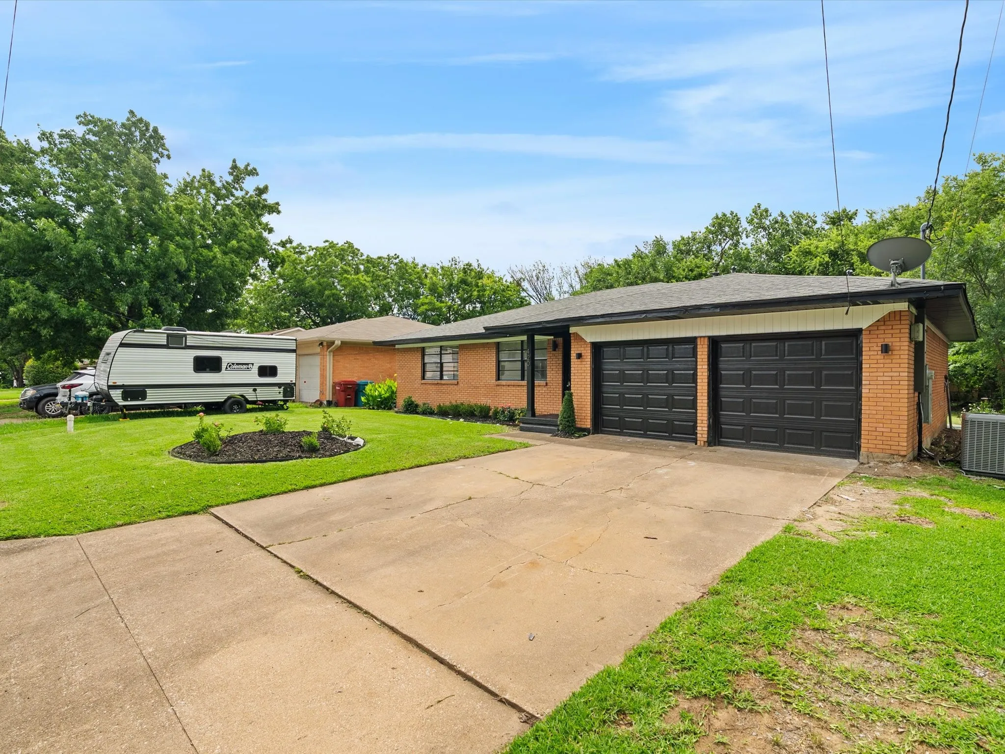 Super cute renovation with a large front yard, large driveway, refreshed landscaping, and painted garage doors and trim.
