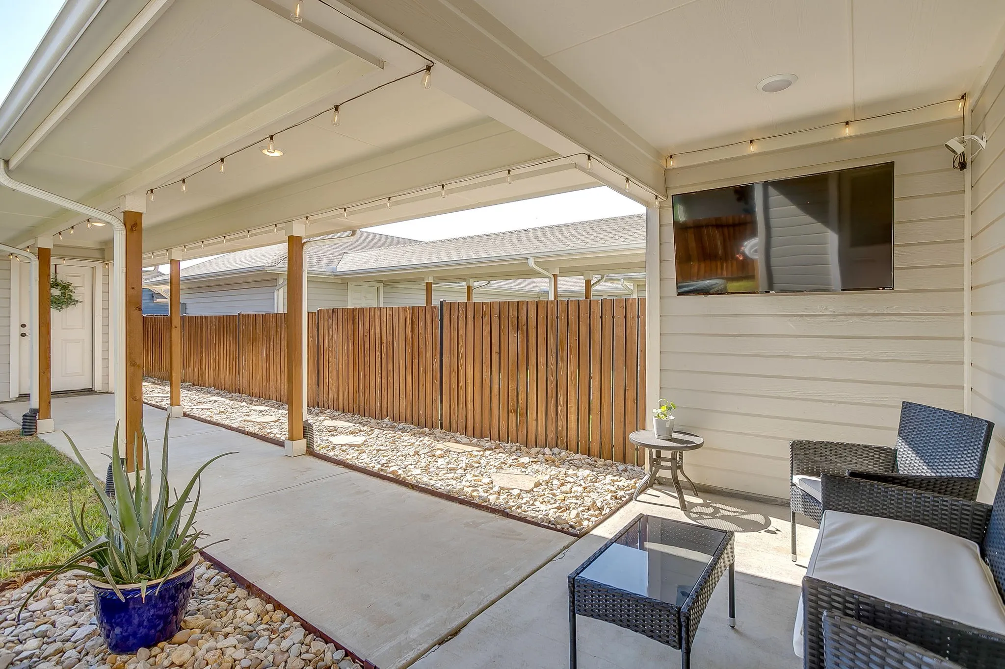 Covered concrete patio featuring string lighting and a mounted television