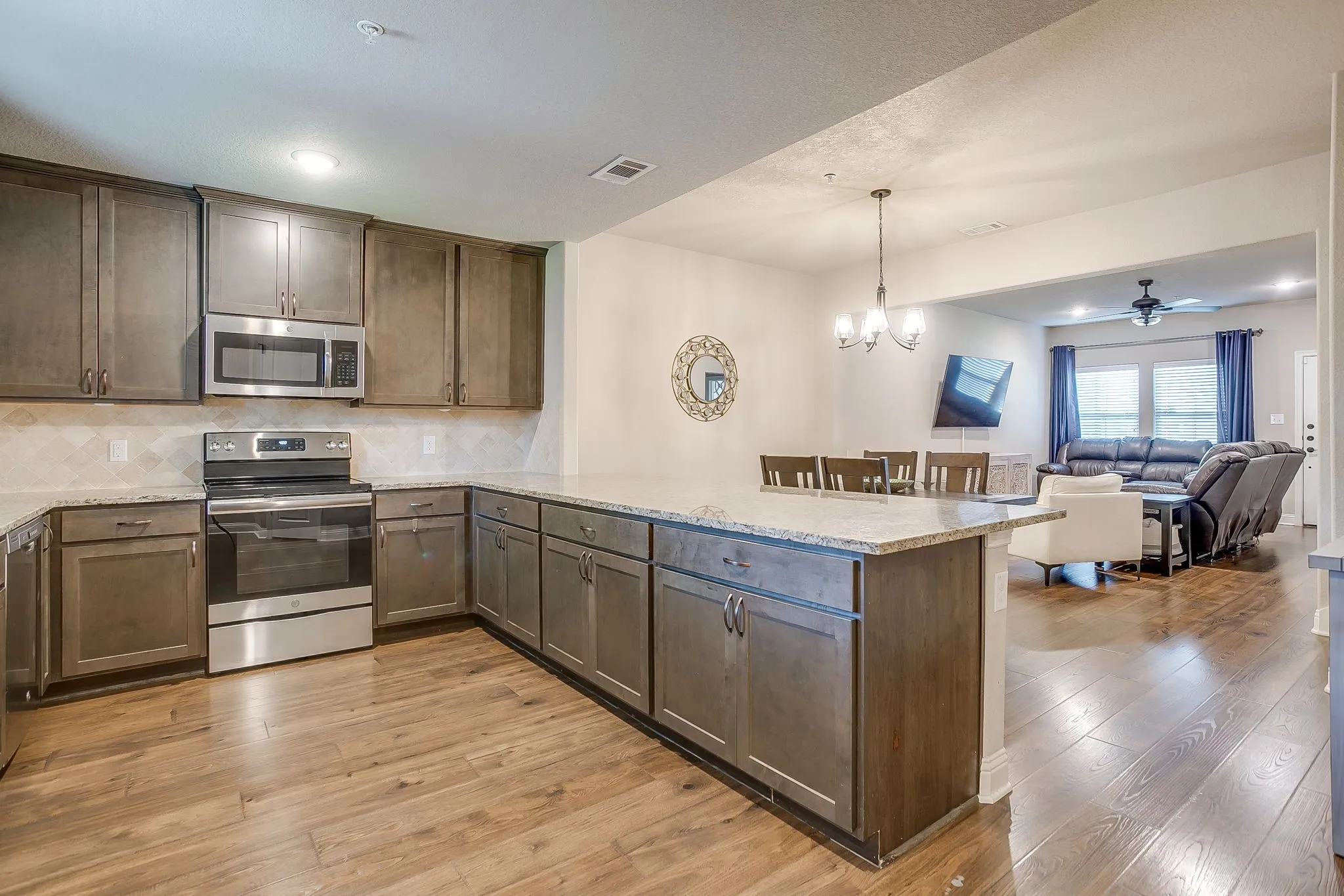 Spacious kitchen featuring wood-finish flooring, stone countertops, stainless steel appliances, and abundant cabinetry