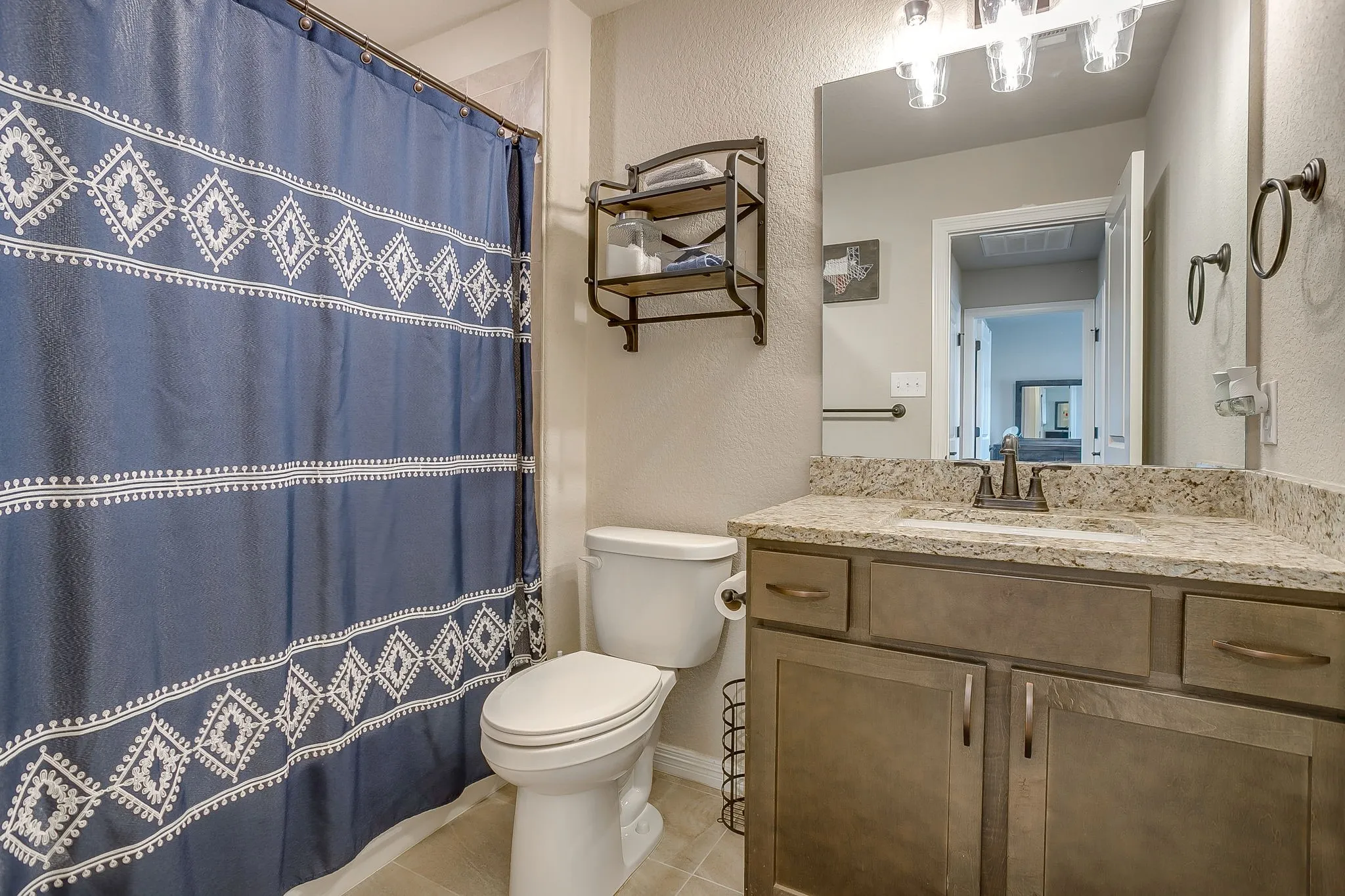 Bathroom vanity featuring a speckled countertop, undermount sink, and dark bronze hardware