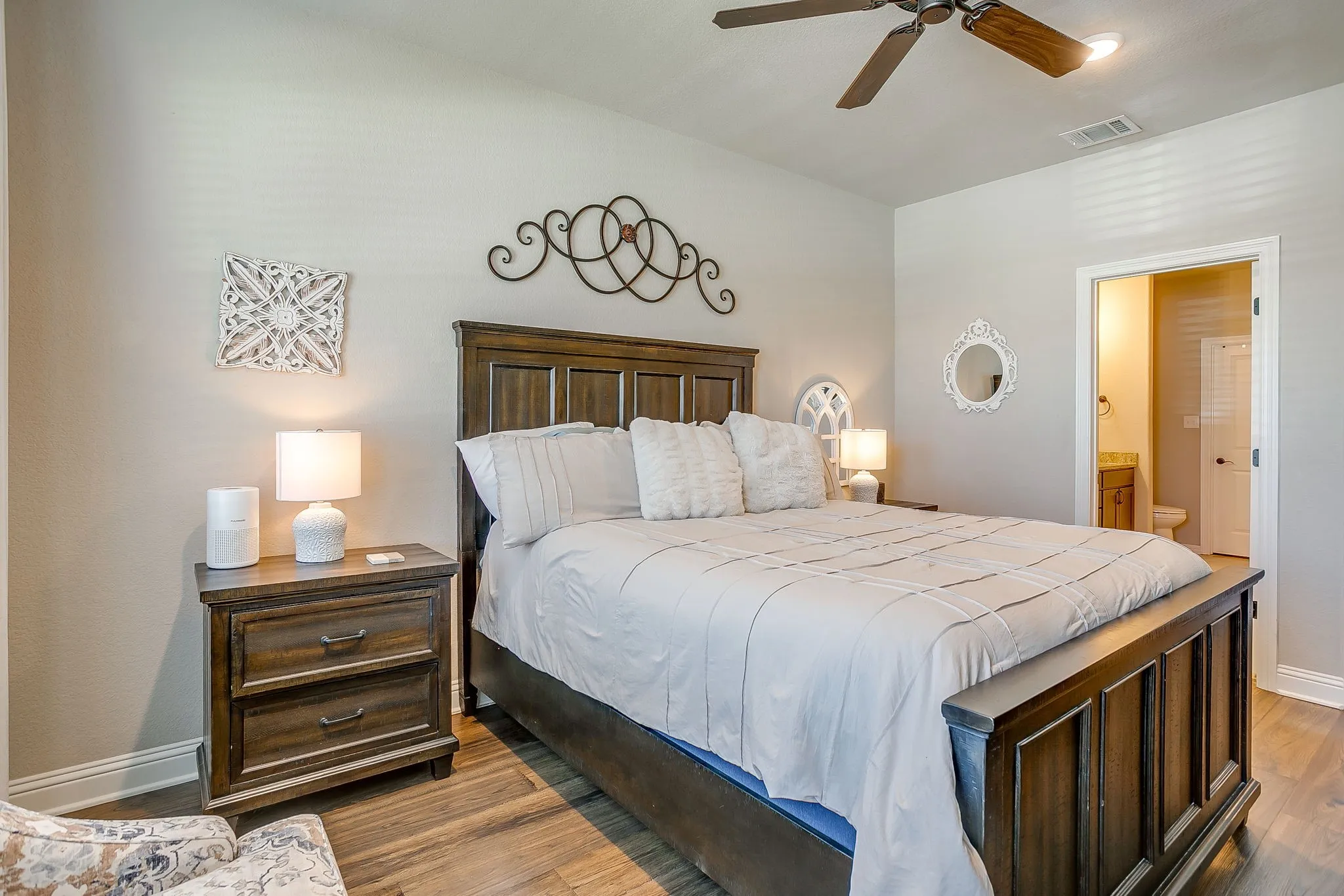 Bedroom featuring wood-finish flooring, a ceiling fan with integrated lighting, and direct access to an en-suite bathroom
