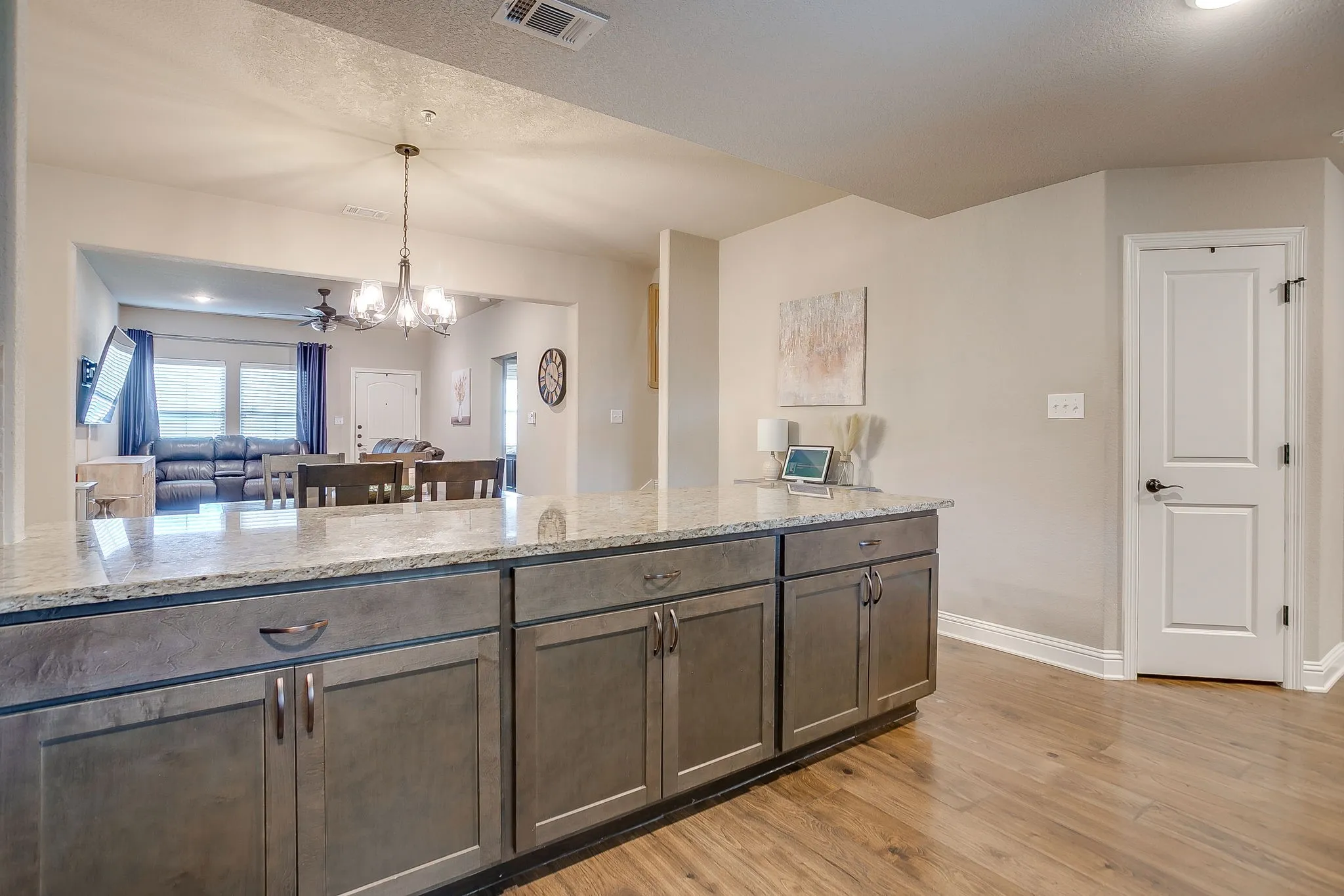 Kitchen island featuring a granite countertop and gray shaker-style cabinetry, wood-finish flooring, and a paneled interior door