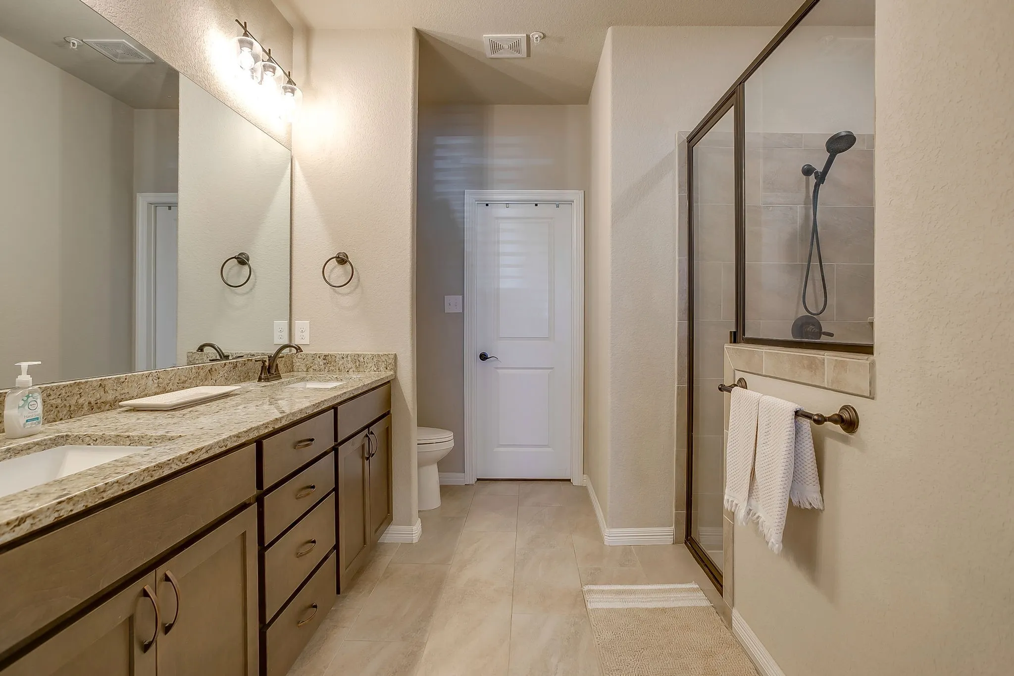 Double vanity with a speckled countertop, undermount sinks, and bronze hardware