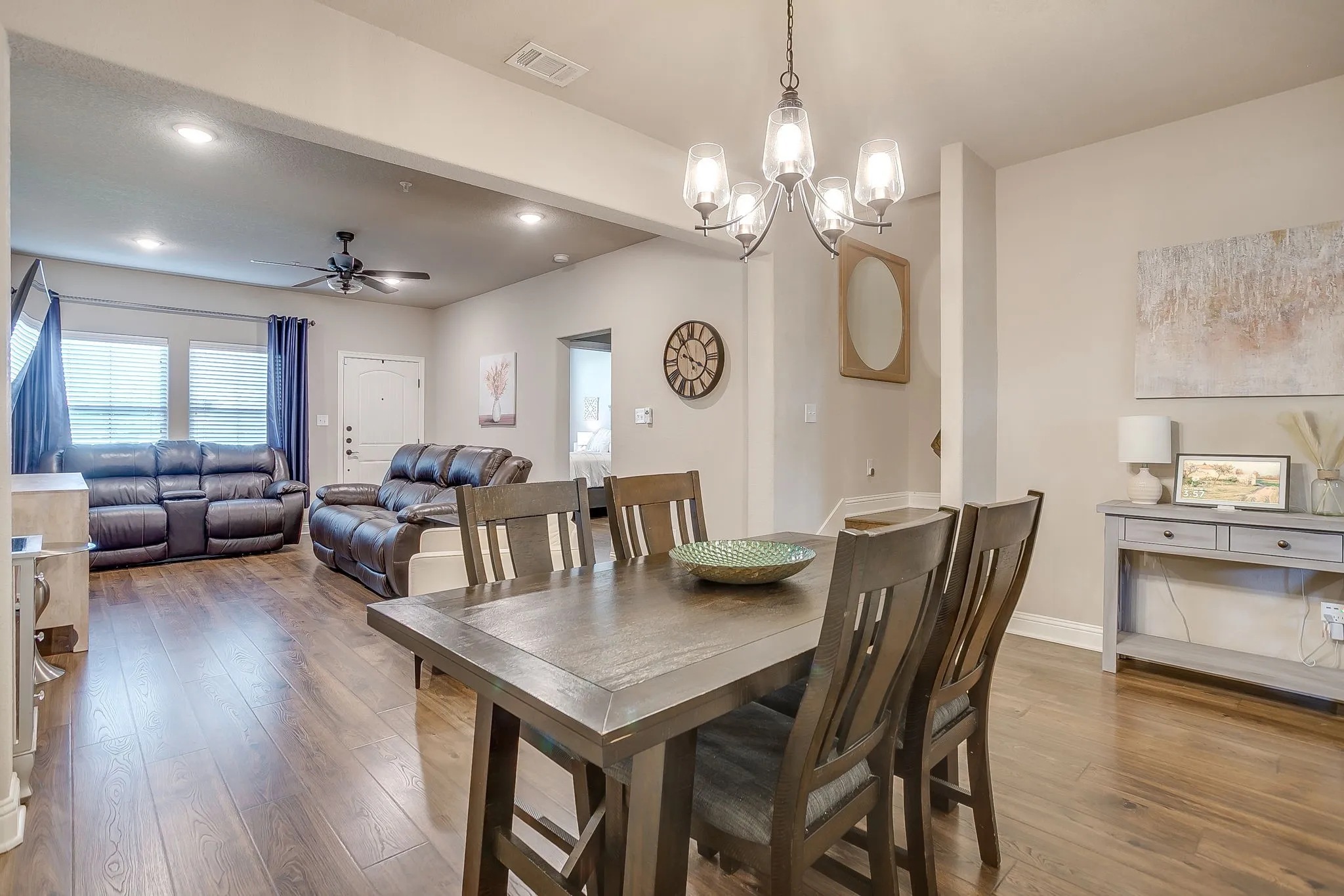 Open-concept living and dining areas featuring wood-finish flooring, recessed lighting, and a chandelier with glass shades