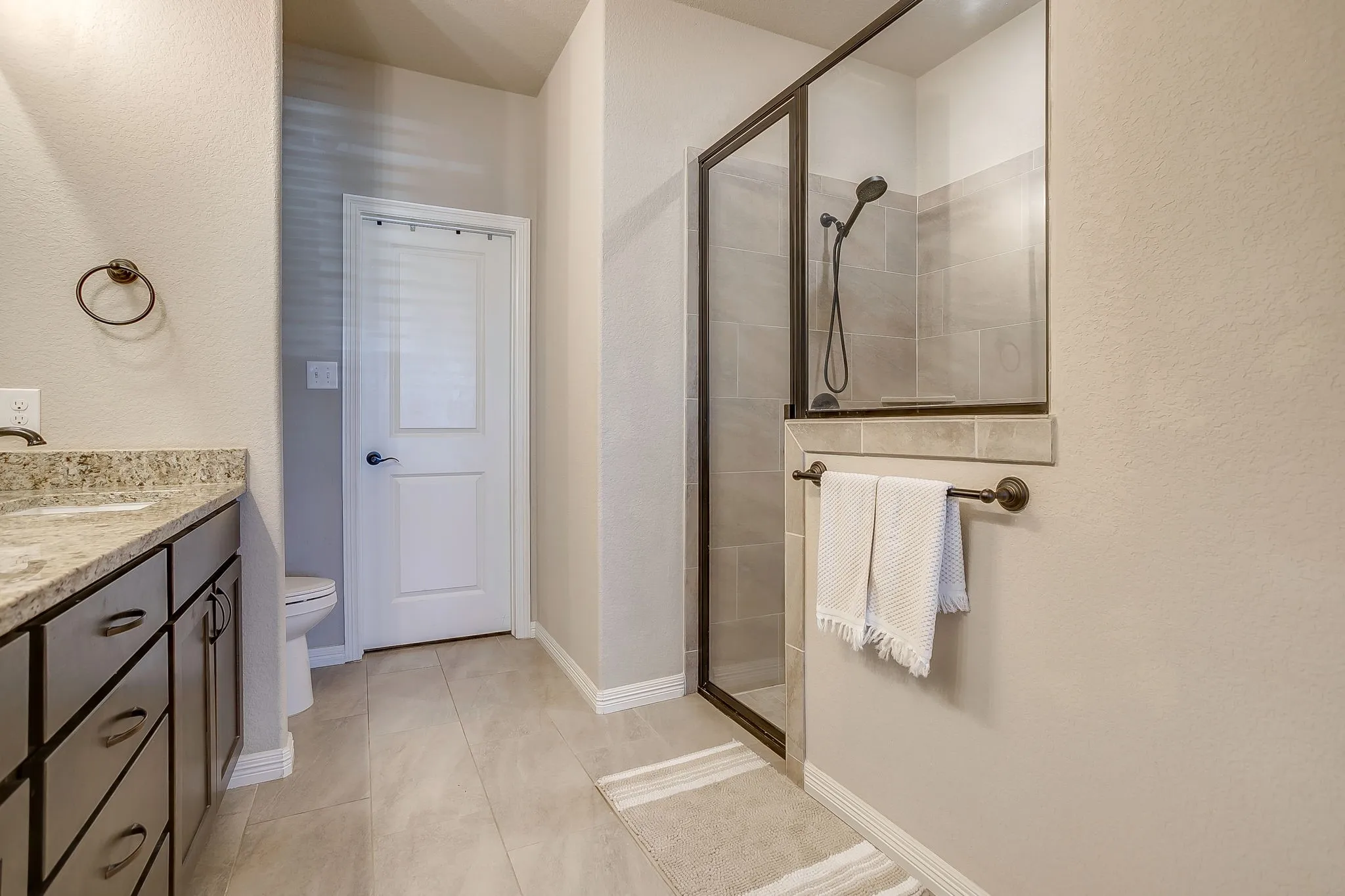 Bathroom featuring a glass-enclosed shower with tiled walls and a dark bronze showerhead