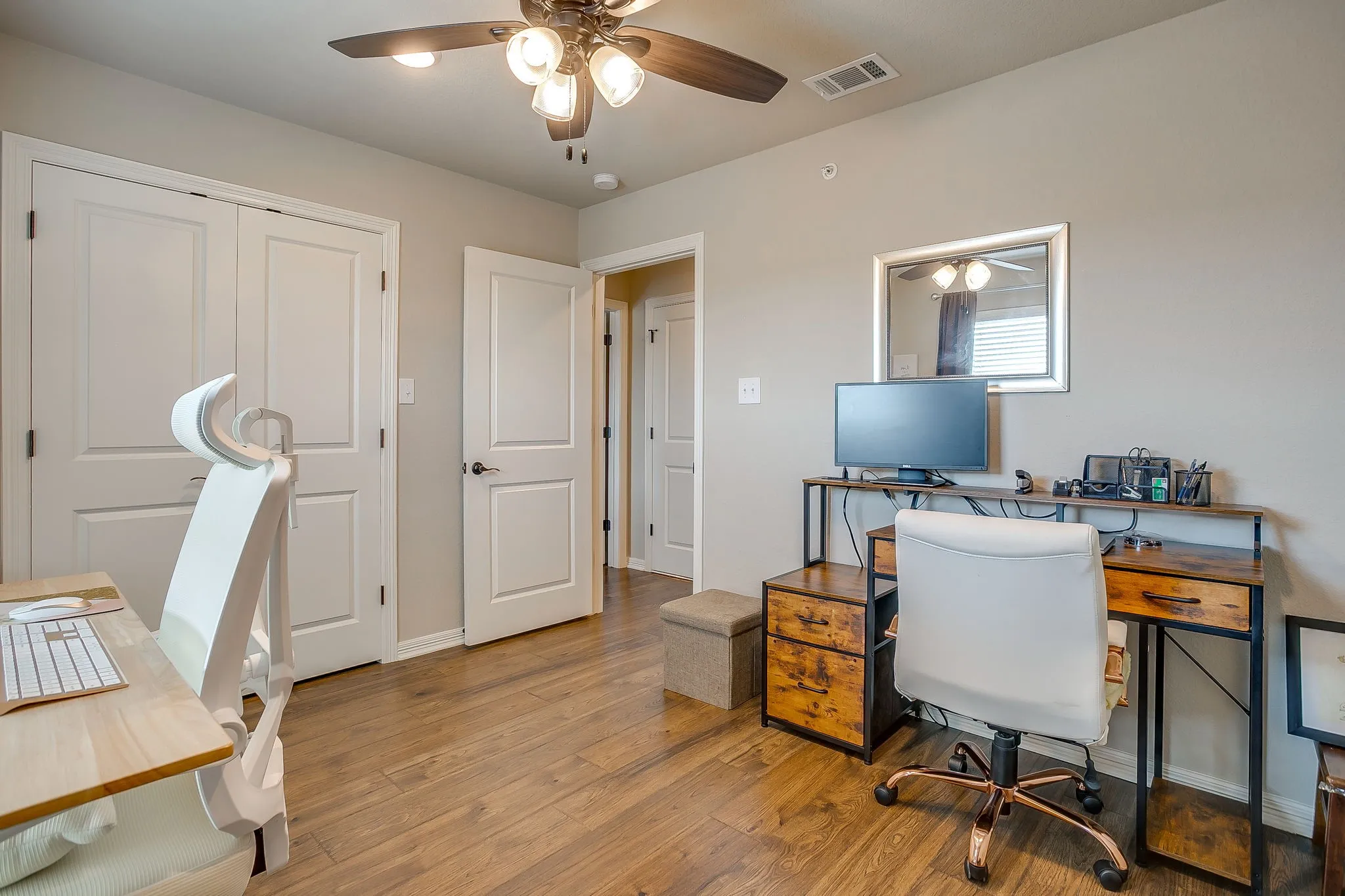 Room with warm wood-finish flooring, light neutral-toned walls, and a ceiling fan with integrated lighting