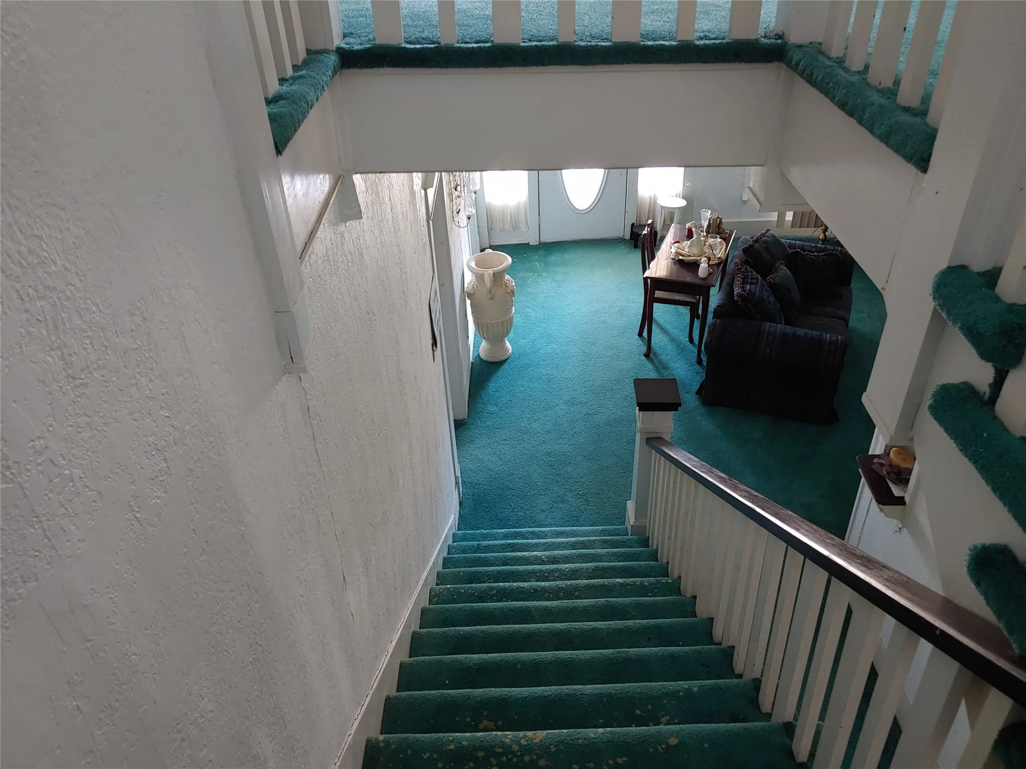 View leading down carpeted staircase with white balusters and dark-finished handrails leading to a lower level with matching carpeting