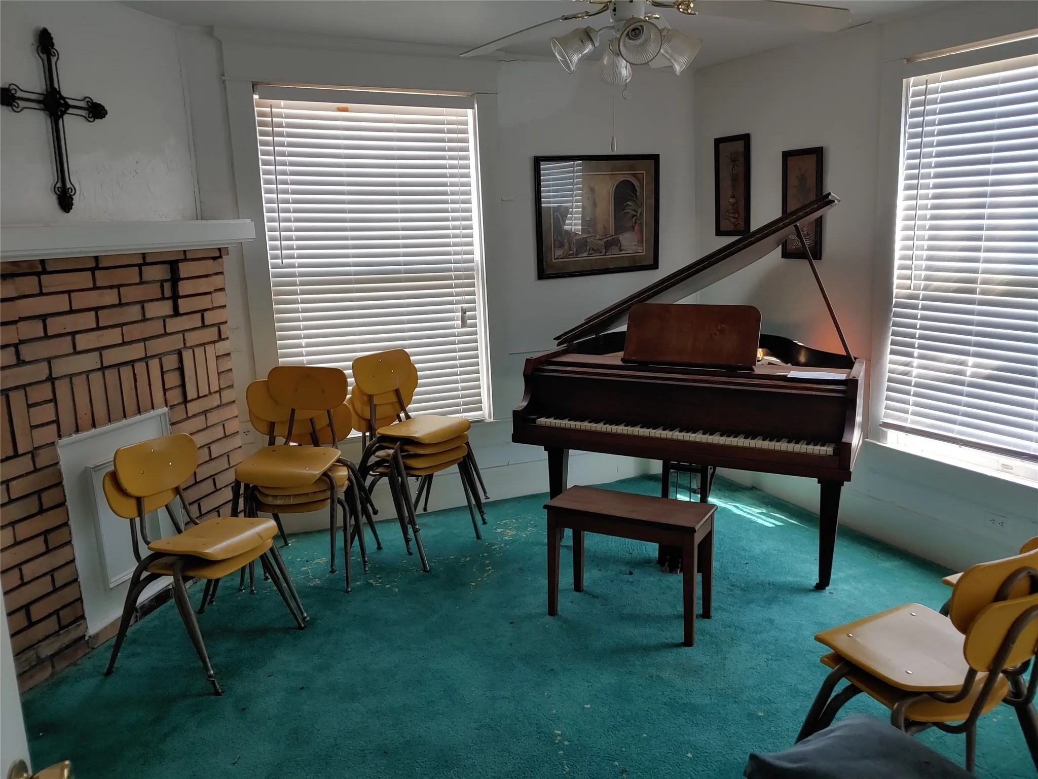 Room featuring brick fireplace with white mantel, two windows with blinds, and green carpeting