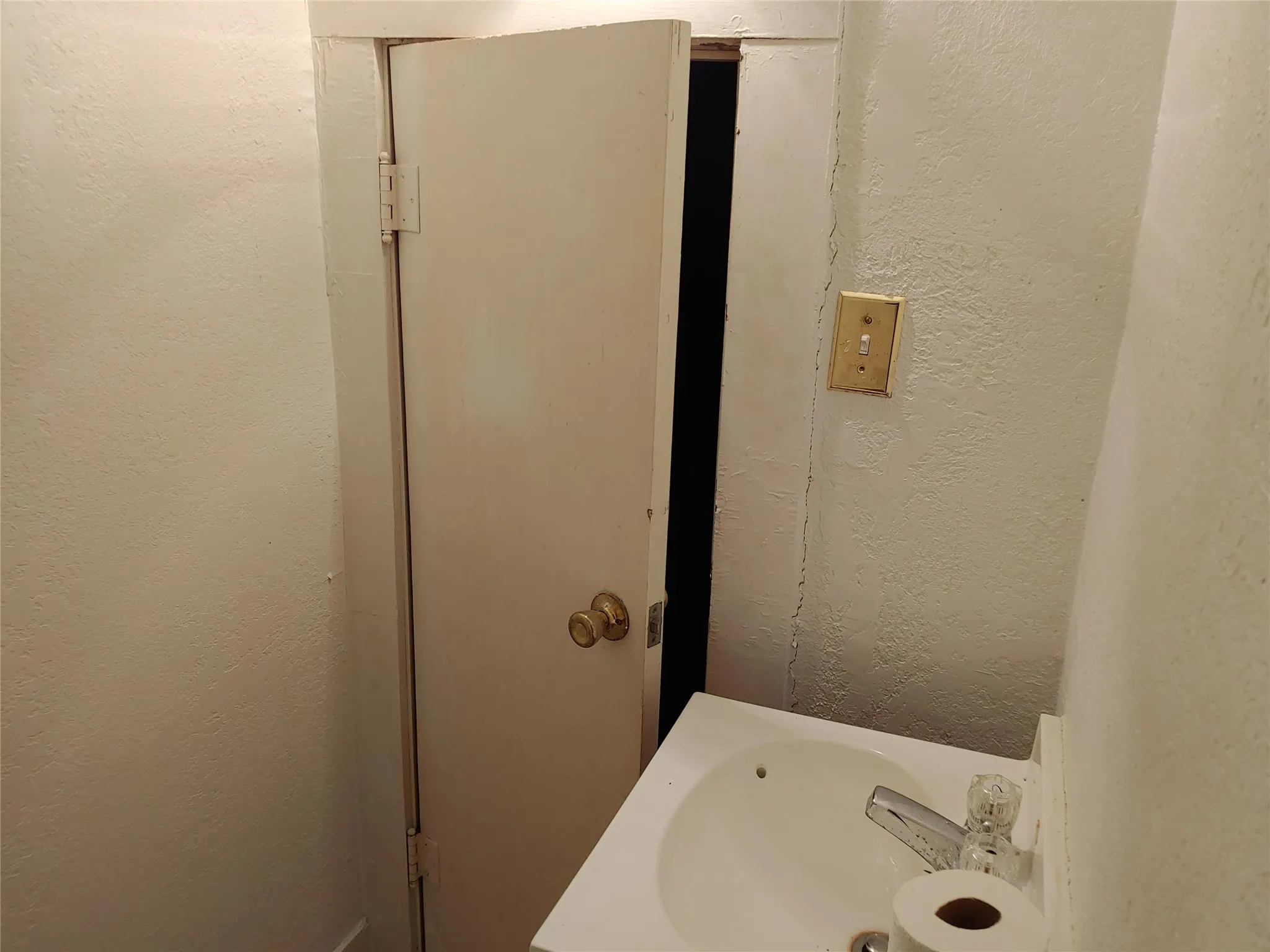Half bath with pedestal sink featuring chrome faucet with clear handles and an adjacent light switch