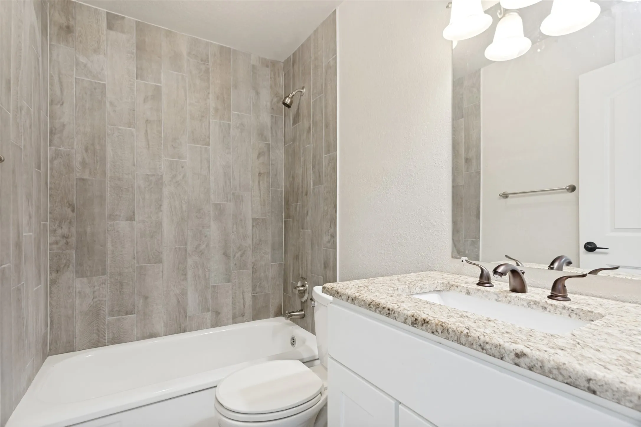 Bathroom with a white vanity featuring a granite-style countertop, dual sinks, and bronze-finish faucets