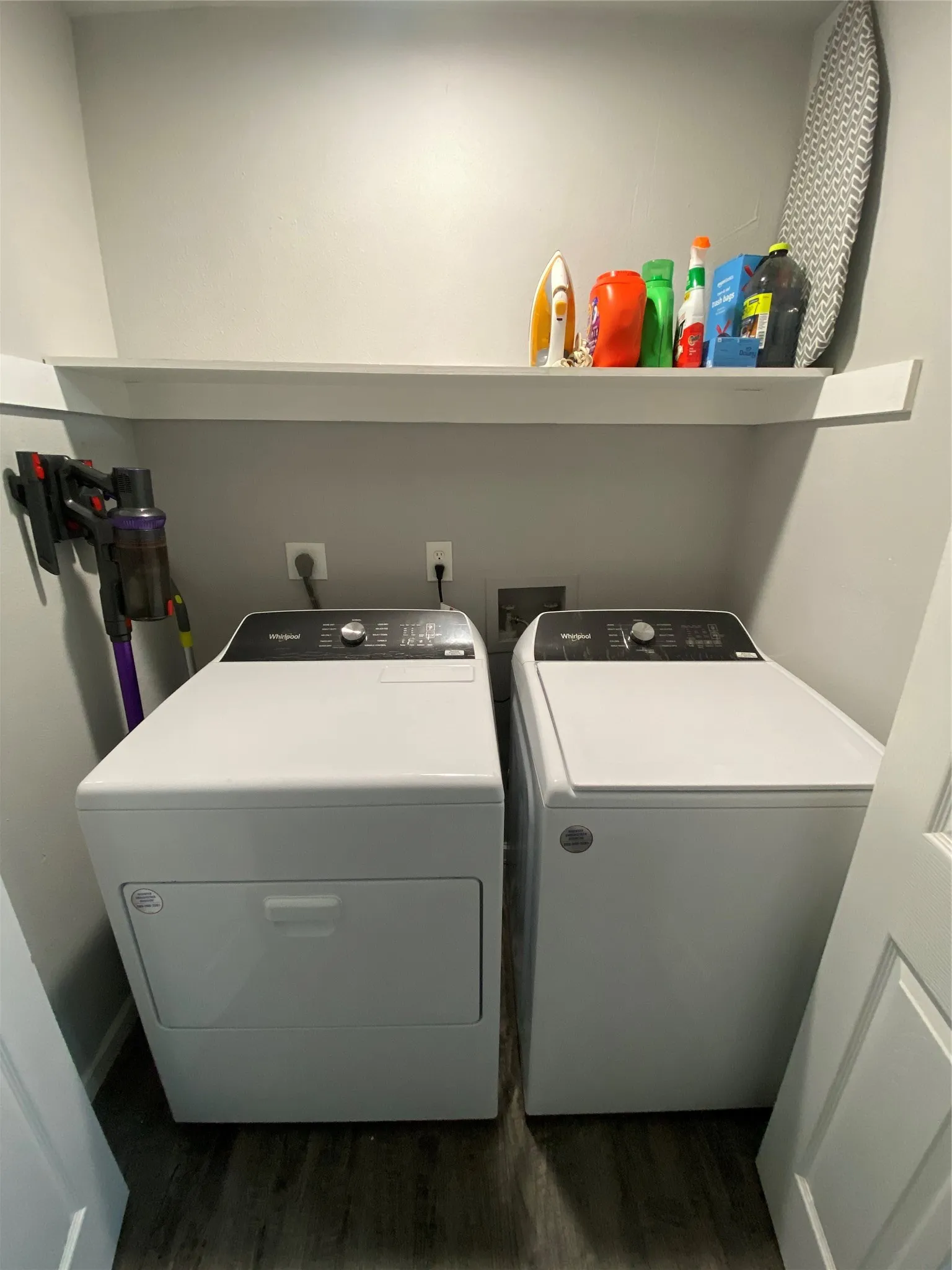 Dedicated laundry area featuring a white floating shelf, neutral wall tones, and wood-finish flooring