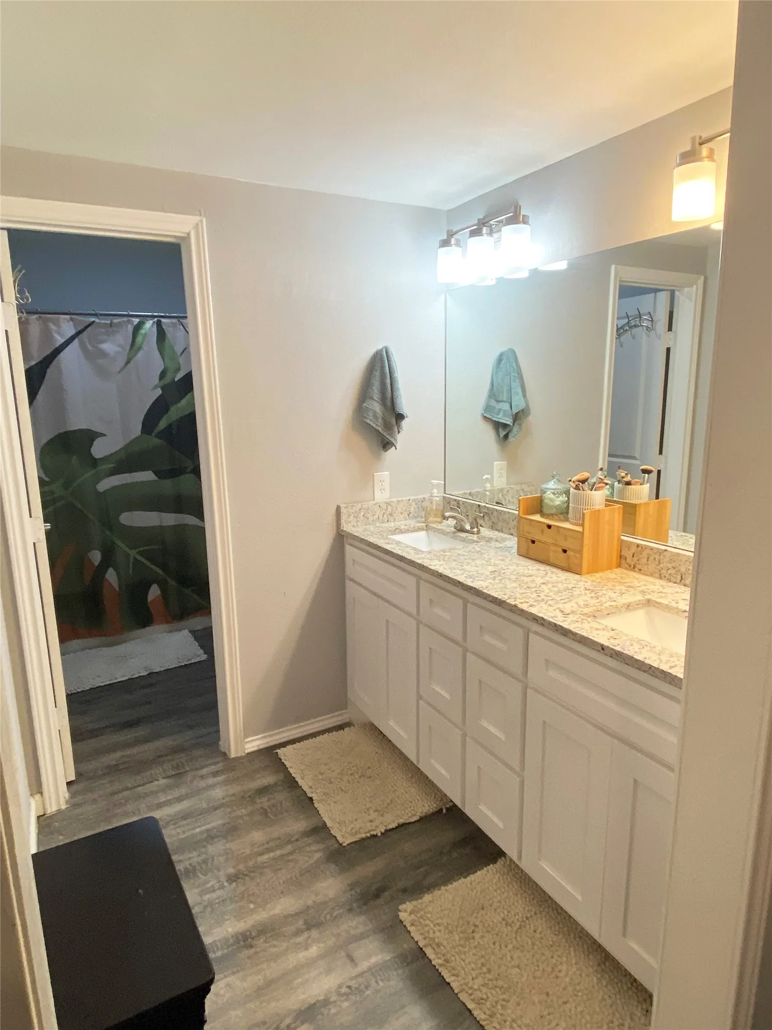Double vanity featuring white cabinetry and light-colored granite countertops