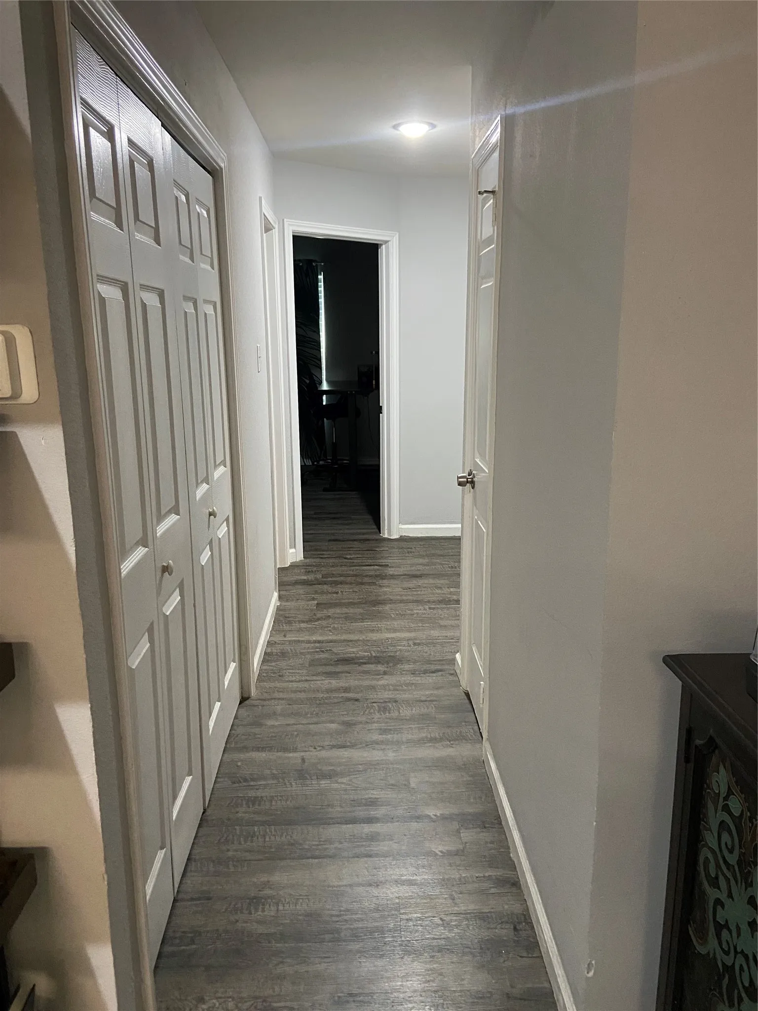Hallway featuring wood-finish flooring, recessed lighting, white walls, and paneled bifold doors (laundry area)