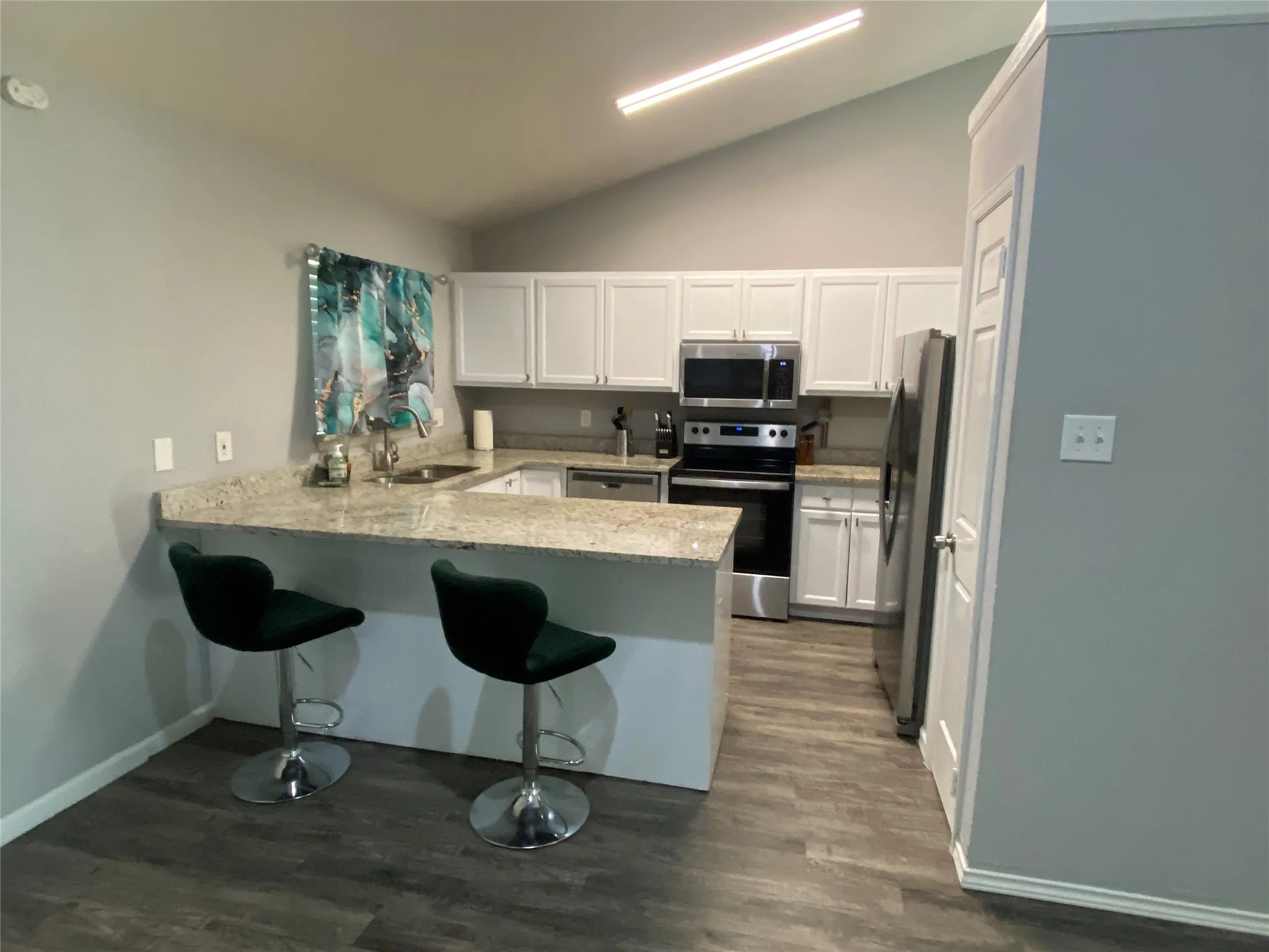 Kitchen featuring a vaulted ceiling with linear lighting, and luxury vinyl plank flooring throughout flooring
