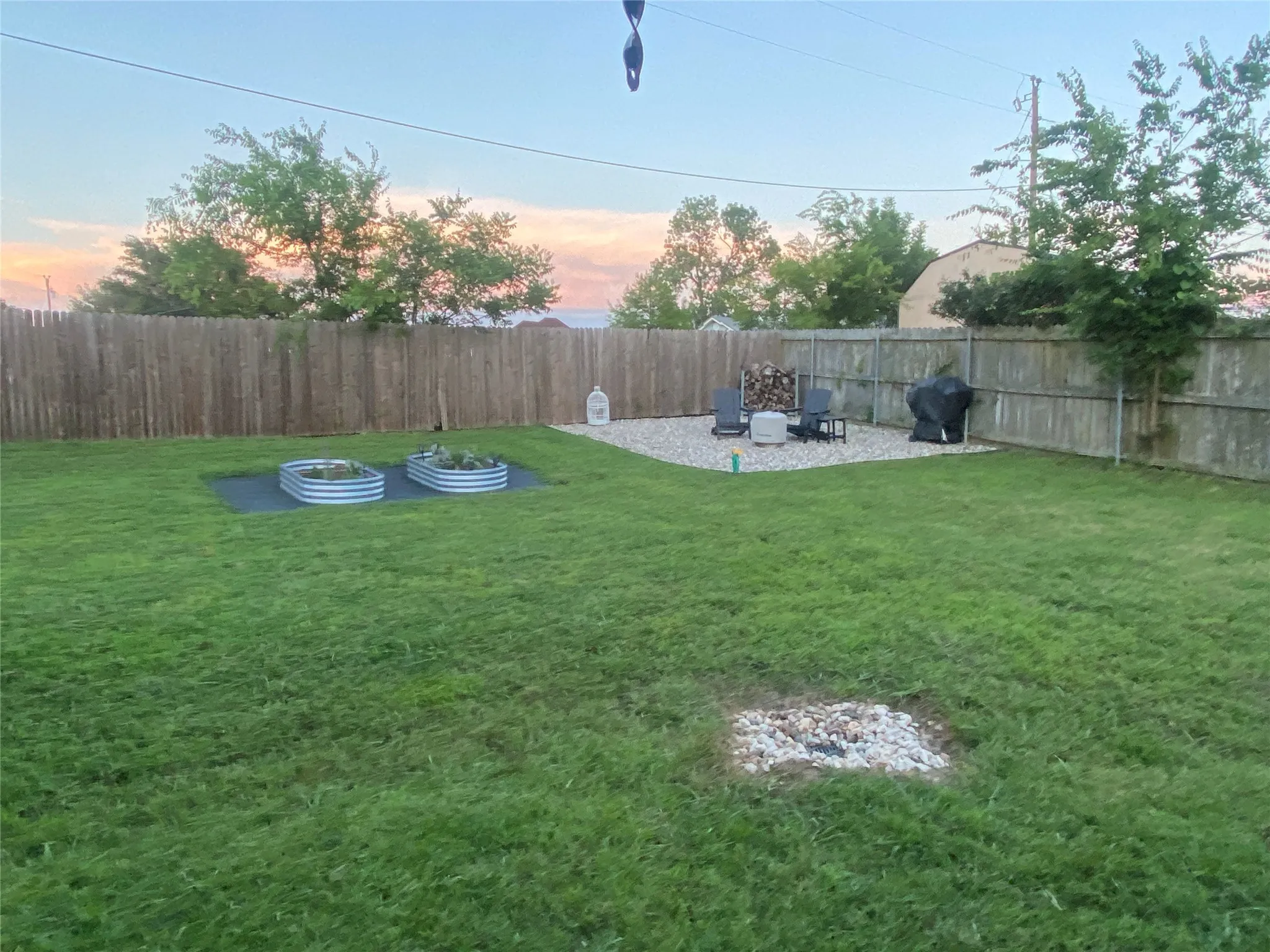 Expansive backyard featuring a privacy fence, a gravel patio area