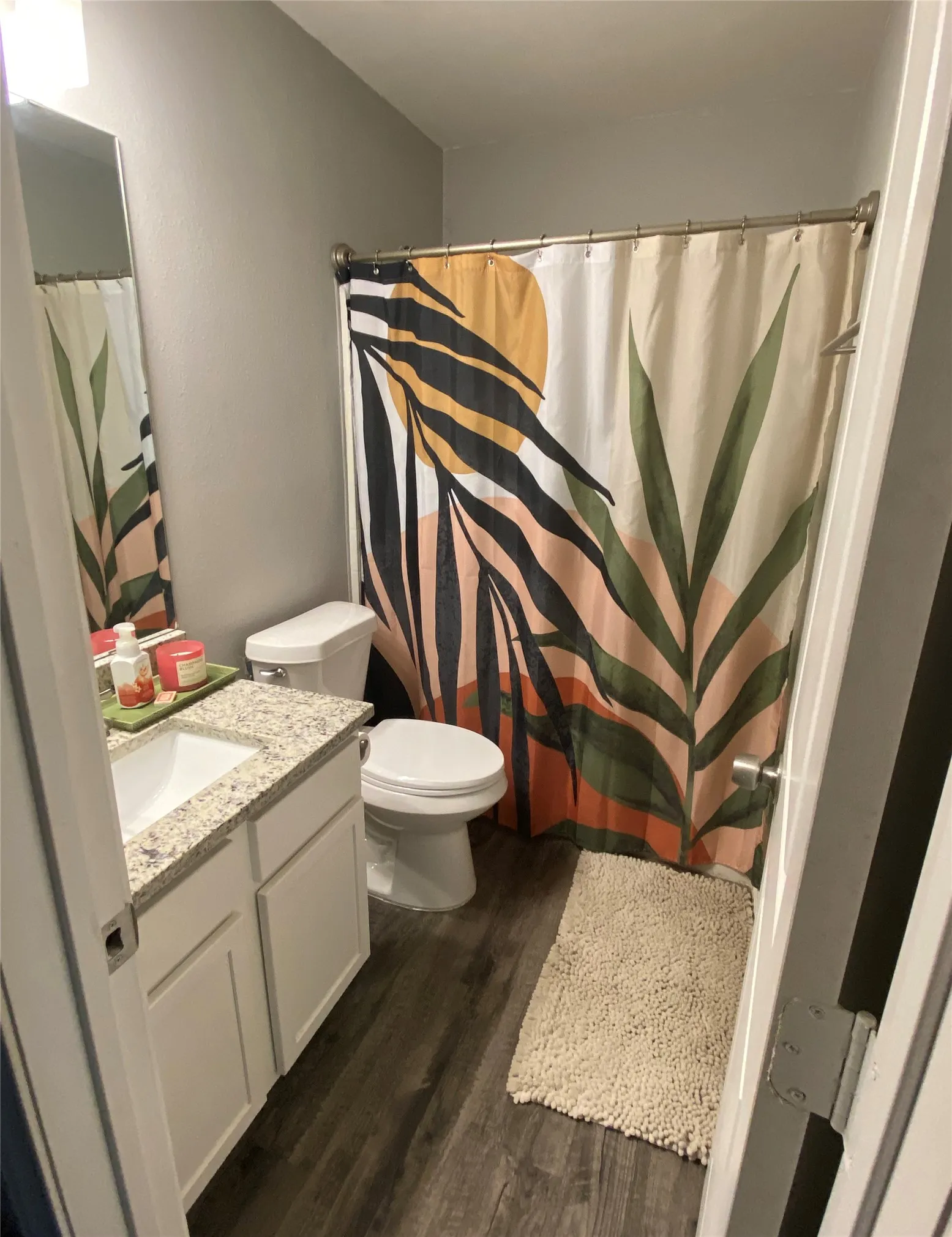 Guest bathroom featuring wood-finish flooring, a white vanity with a granite countertop