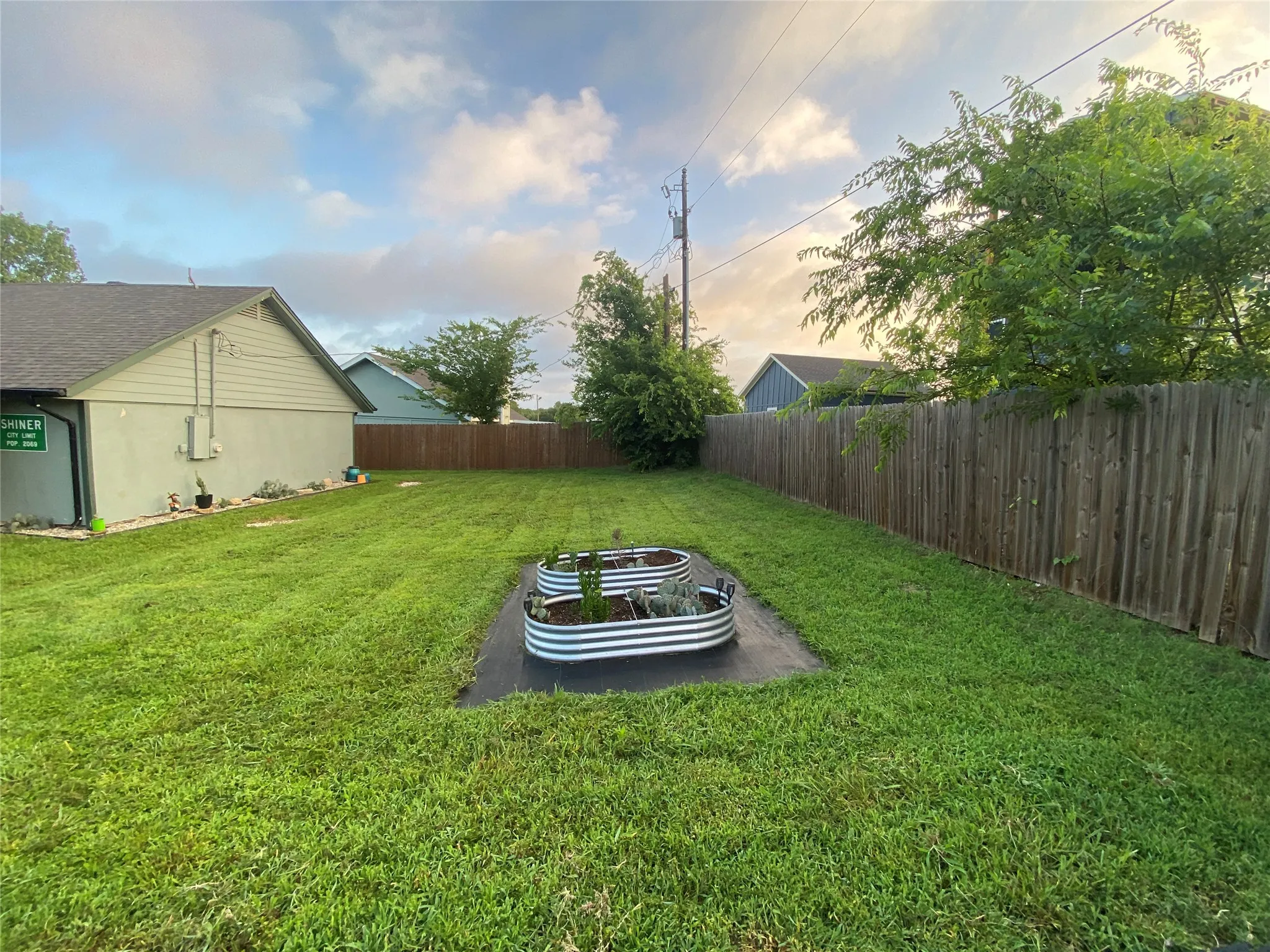 Manicured lawn, full privacy fencing, and two galvanized steel raised garden beds