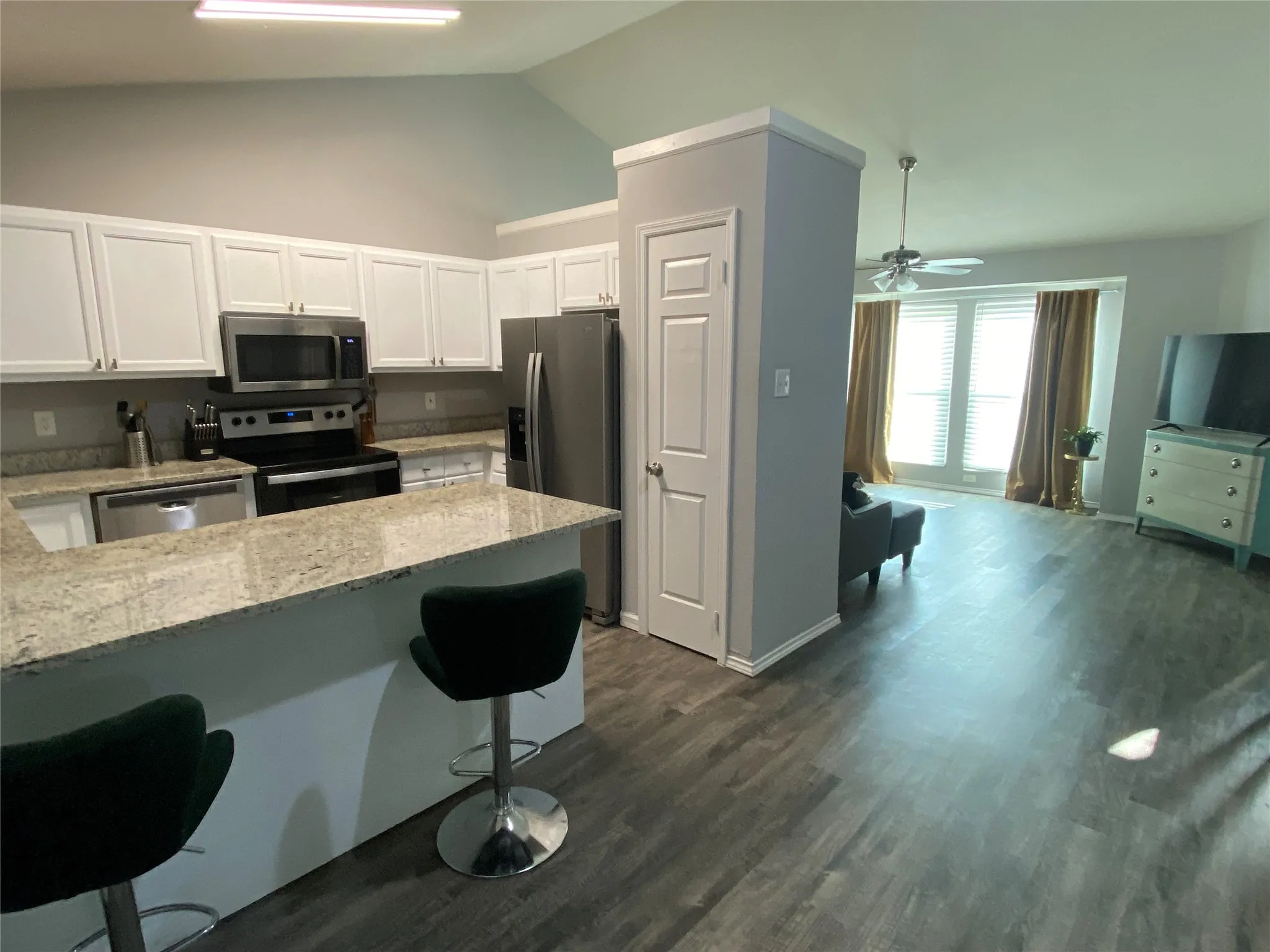 Kitchen featuring white cabinetry, stainless steel appliances, and a breakfast bar with granite countertops