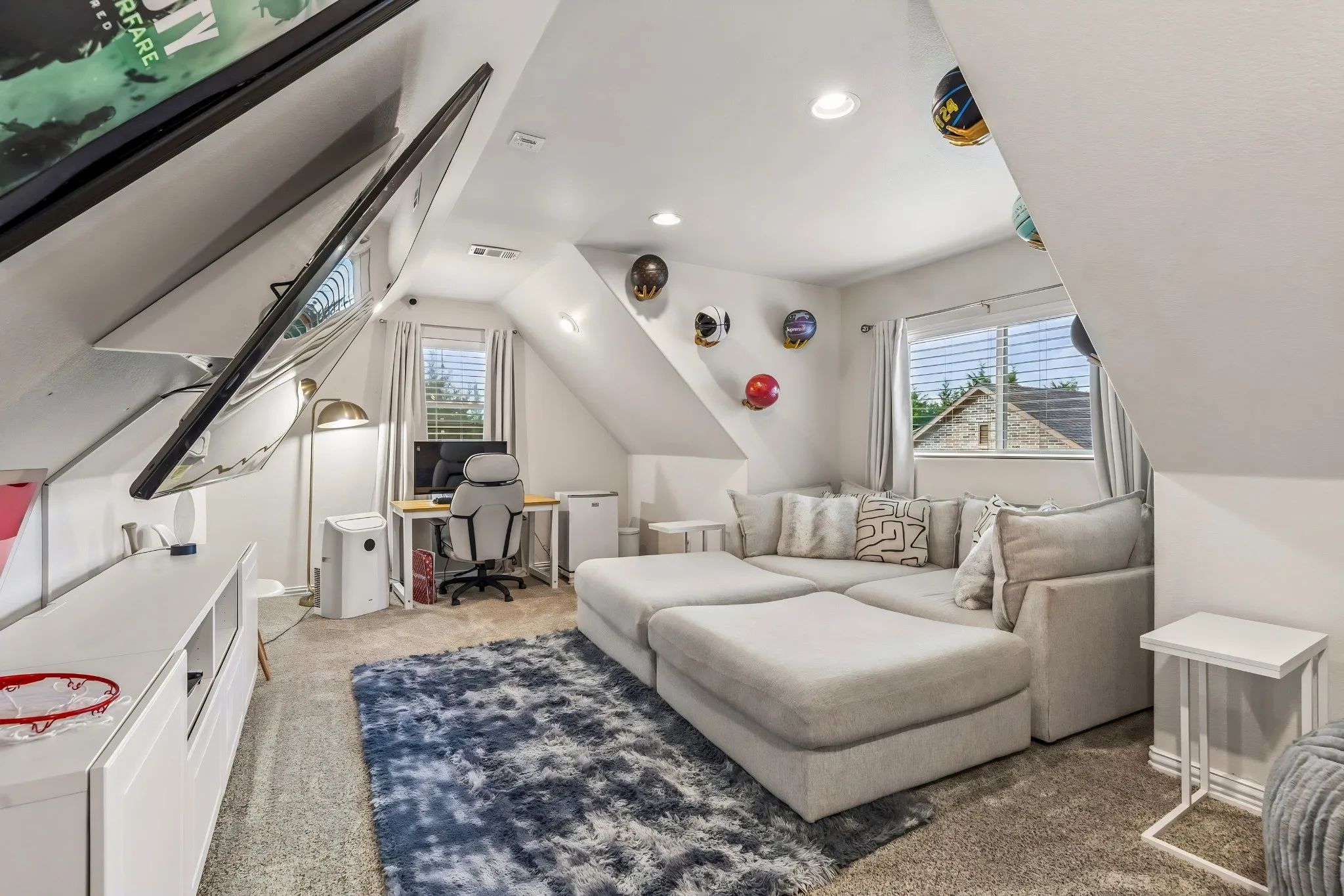 Carpeted room with sloped ceilings, recessed lighting, built-in shelving, and multiple windows
