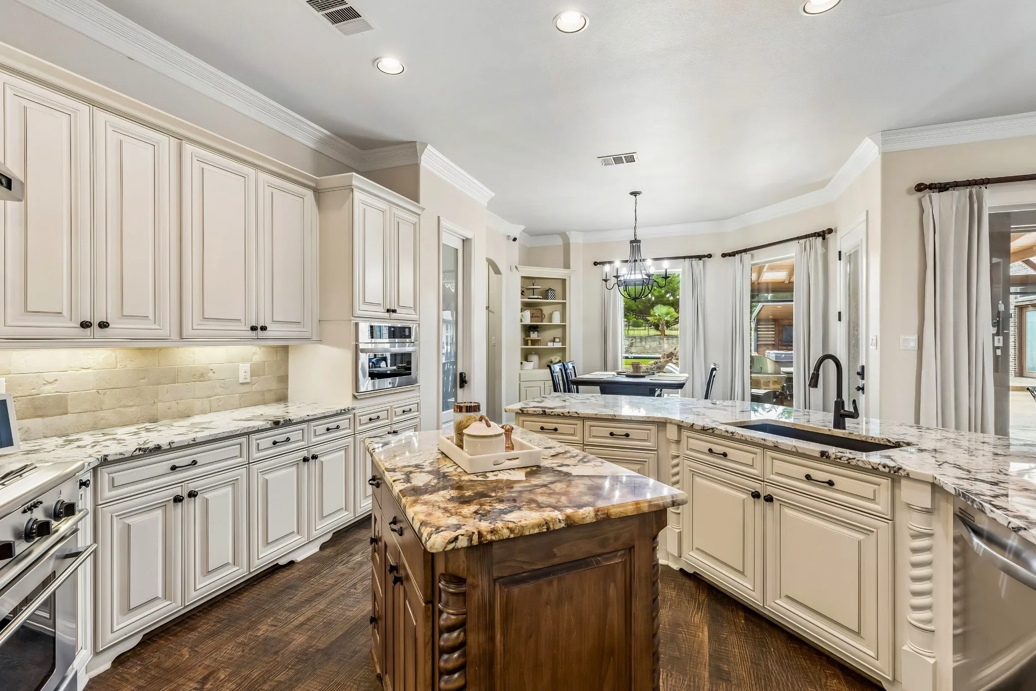Gourmet kitchen featuring white cabinetry, stone countertops, a multi-tone island, wood-finish flooring, and integrated stainless steel appliances