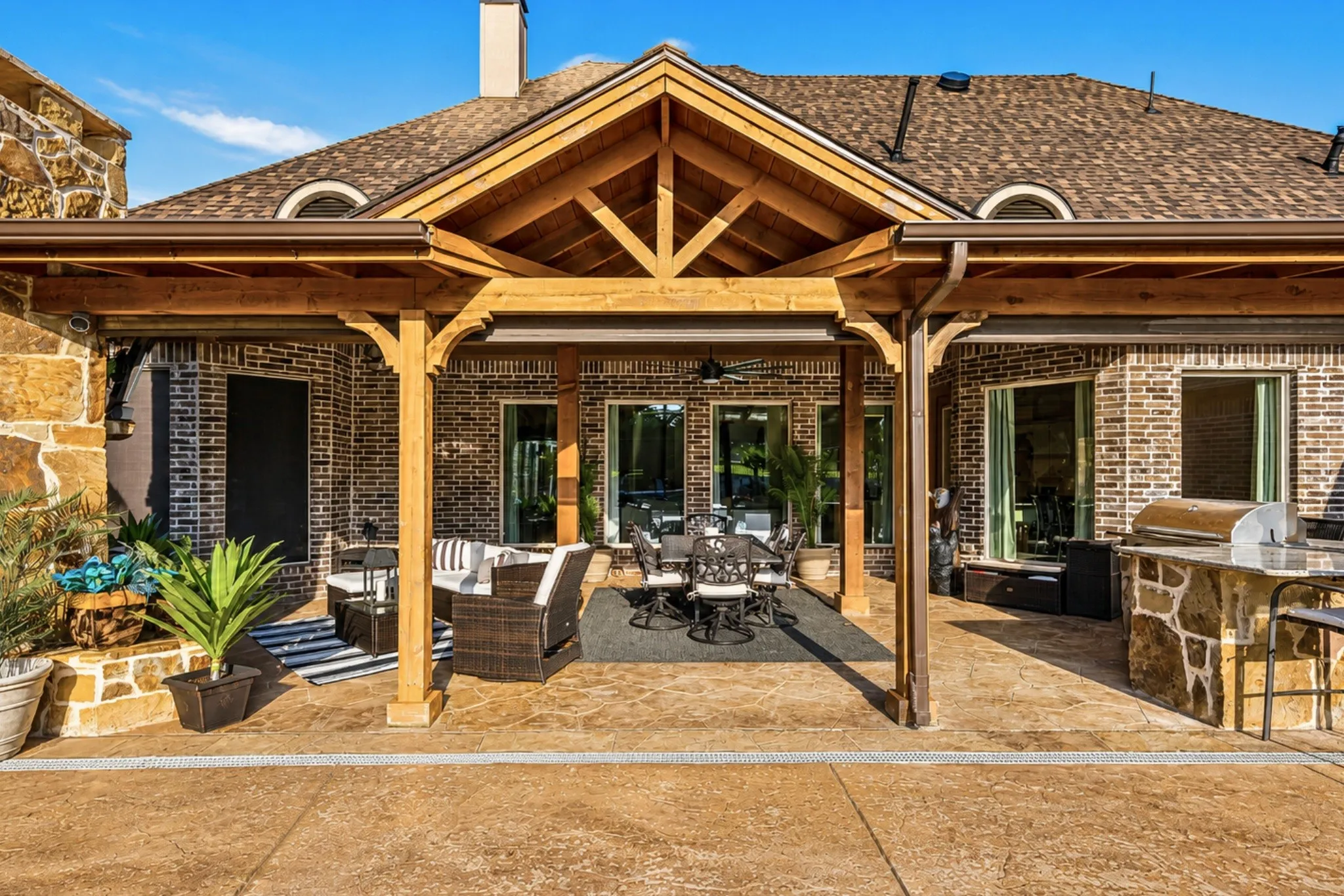 Expansive covered patio featuring a wood-beam vaulted ceiling and stamped concrete flooring
