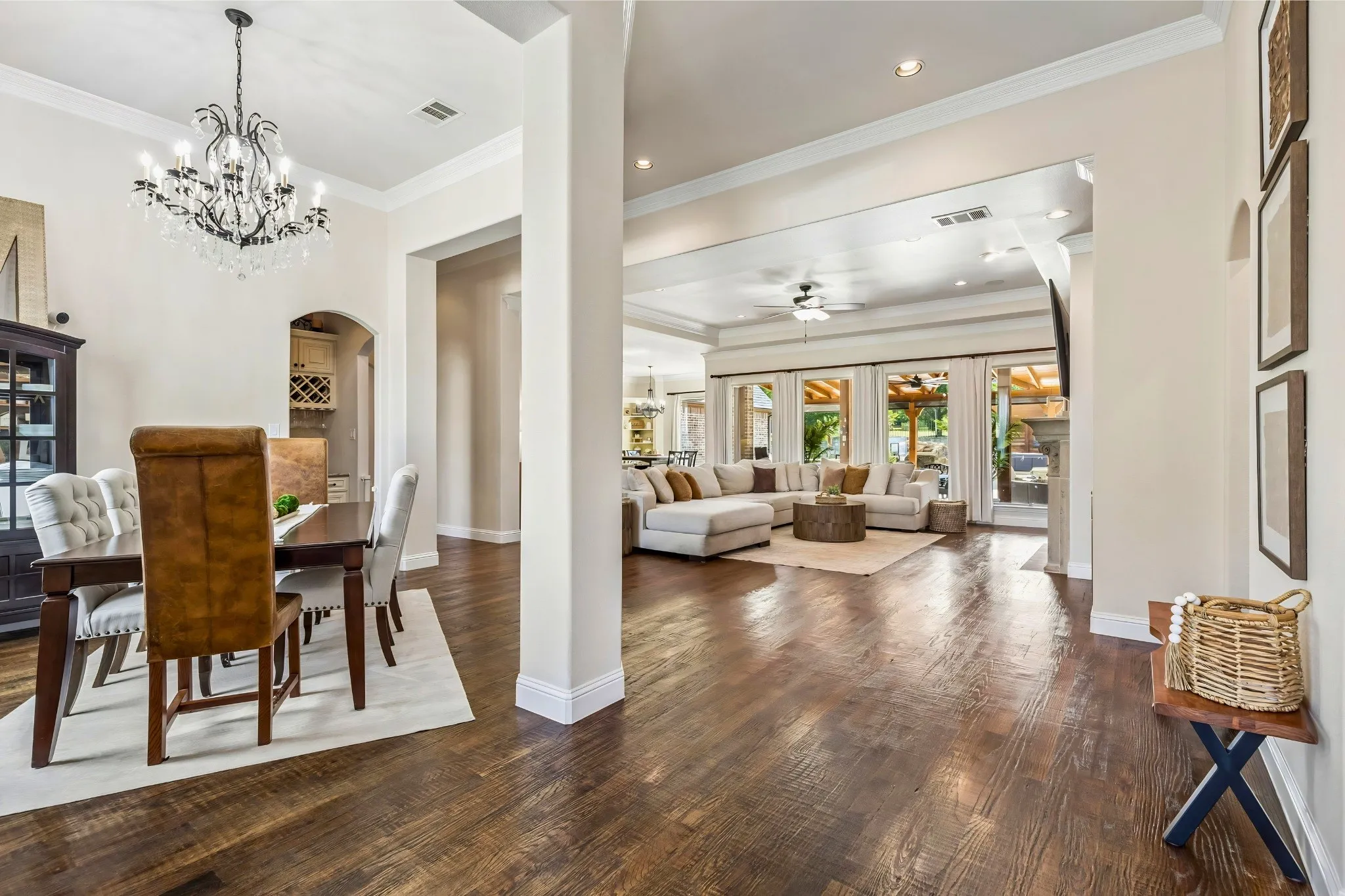 Wood-finish flooring throughout, featuring a dining area with an ornate chandelier and an arched entryway to a built-in wine rack