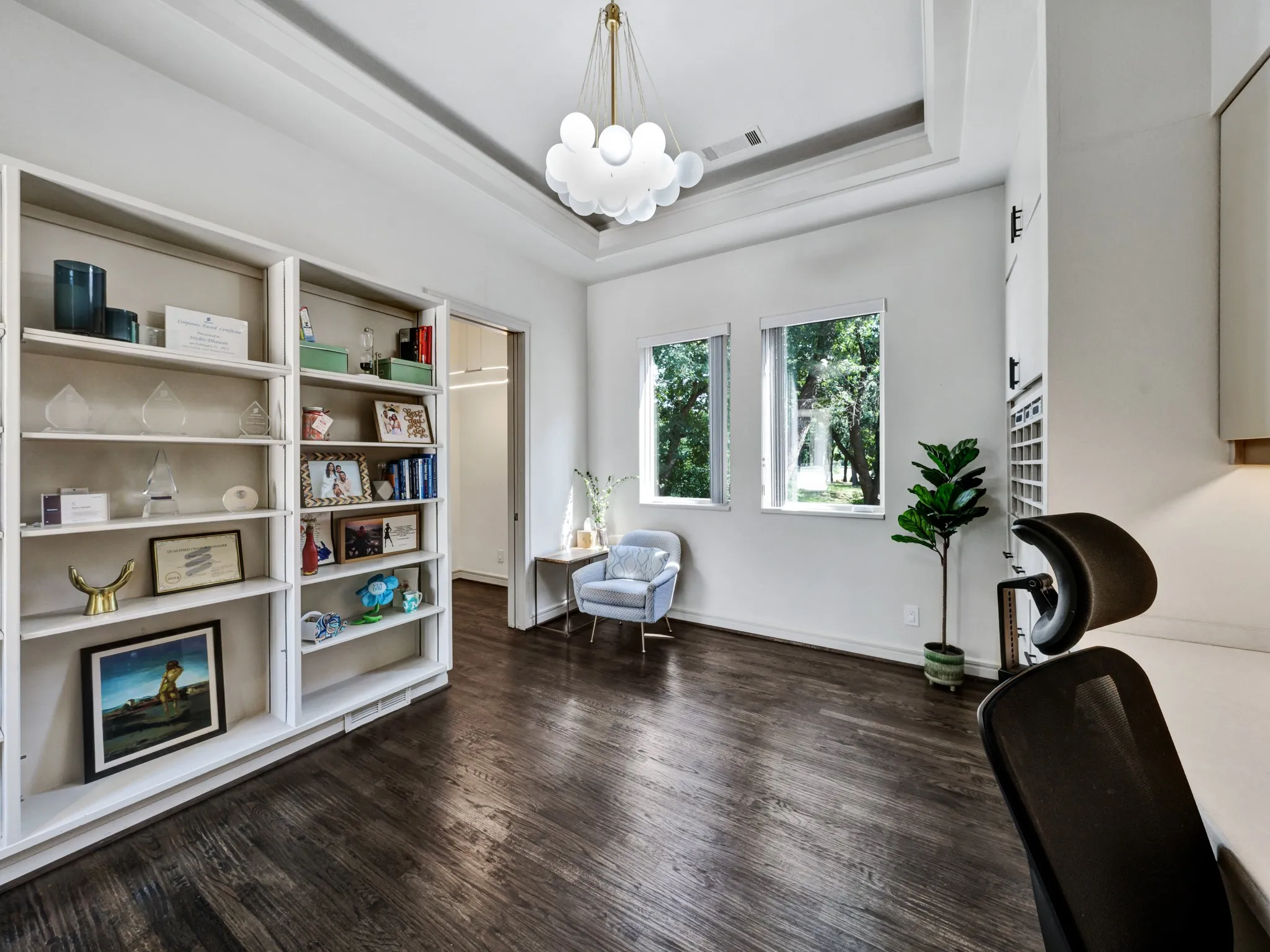 Dedicated office space featuring extensive built-in cabinetry, under-cabinet lighting, a long integrated desk surface, and dark wood-finish flooring