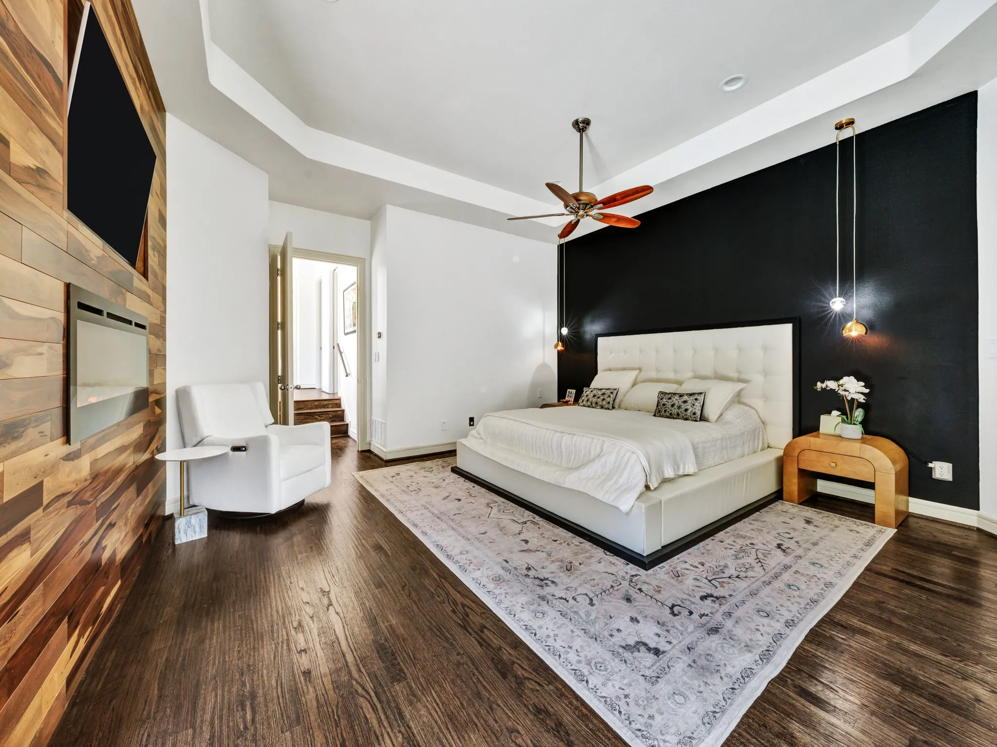 Hardwood flooring with a decorative area rug, complemented by a recessed electric fireplace and a wood-paneled accent wall