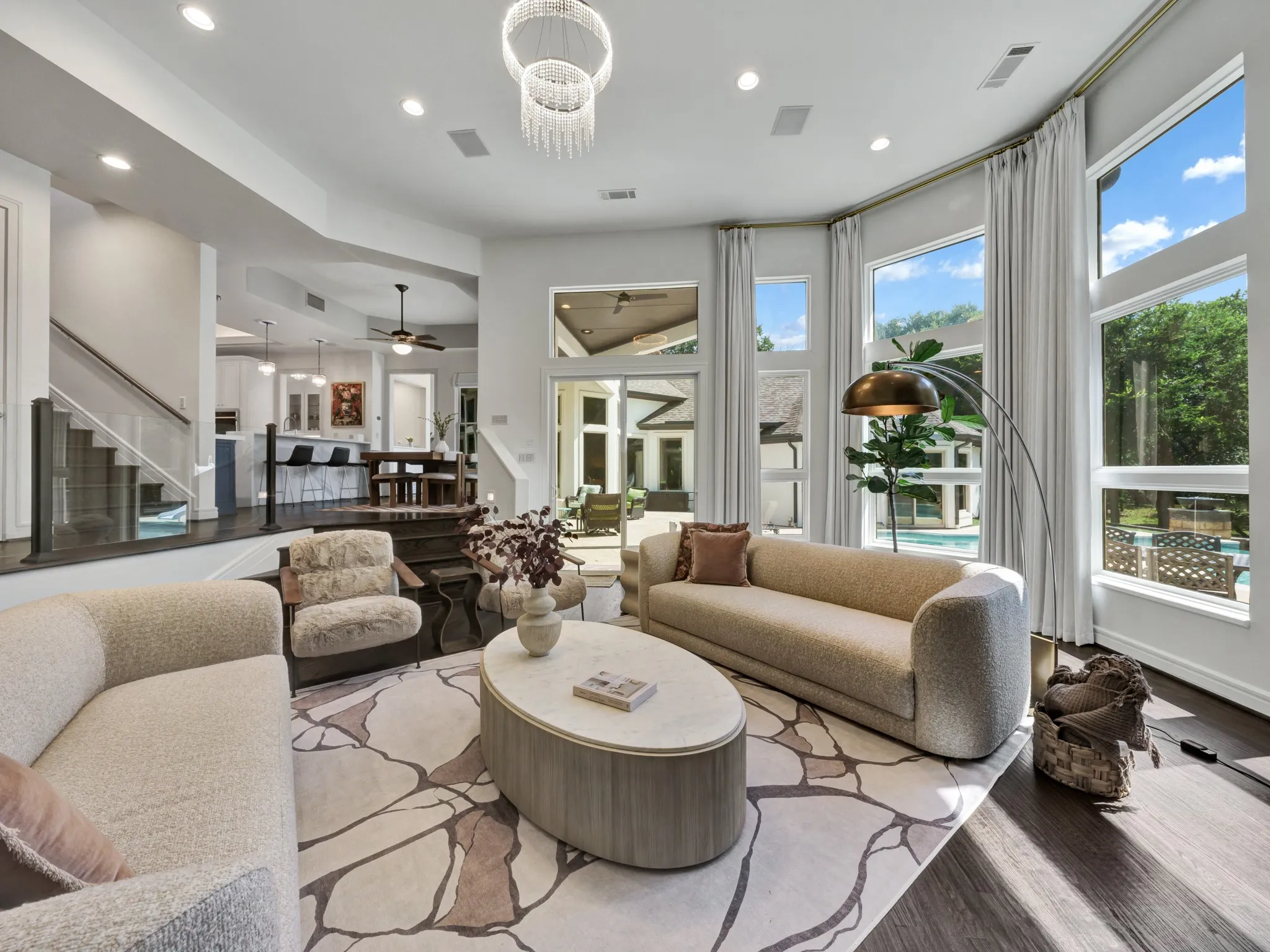 Spacious living area featuring expansive windows, dark wood-finish flooring, a contemporary chandelier