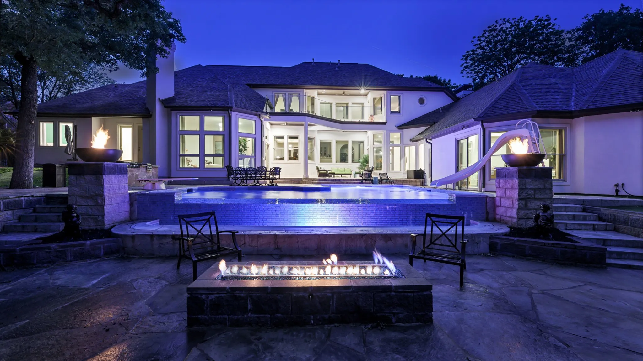 Outdoor swimming pool with integrated spa and rock-finish surround