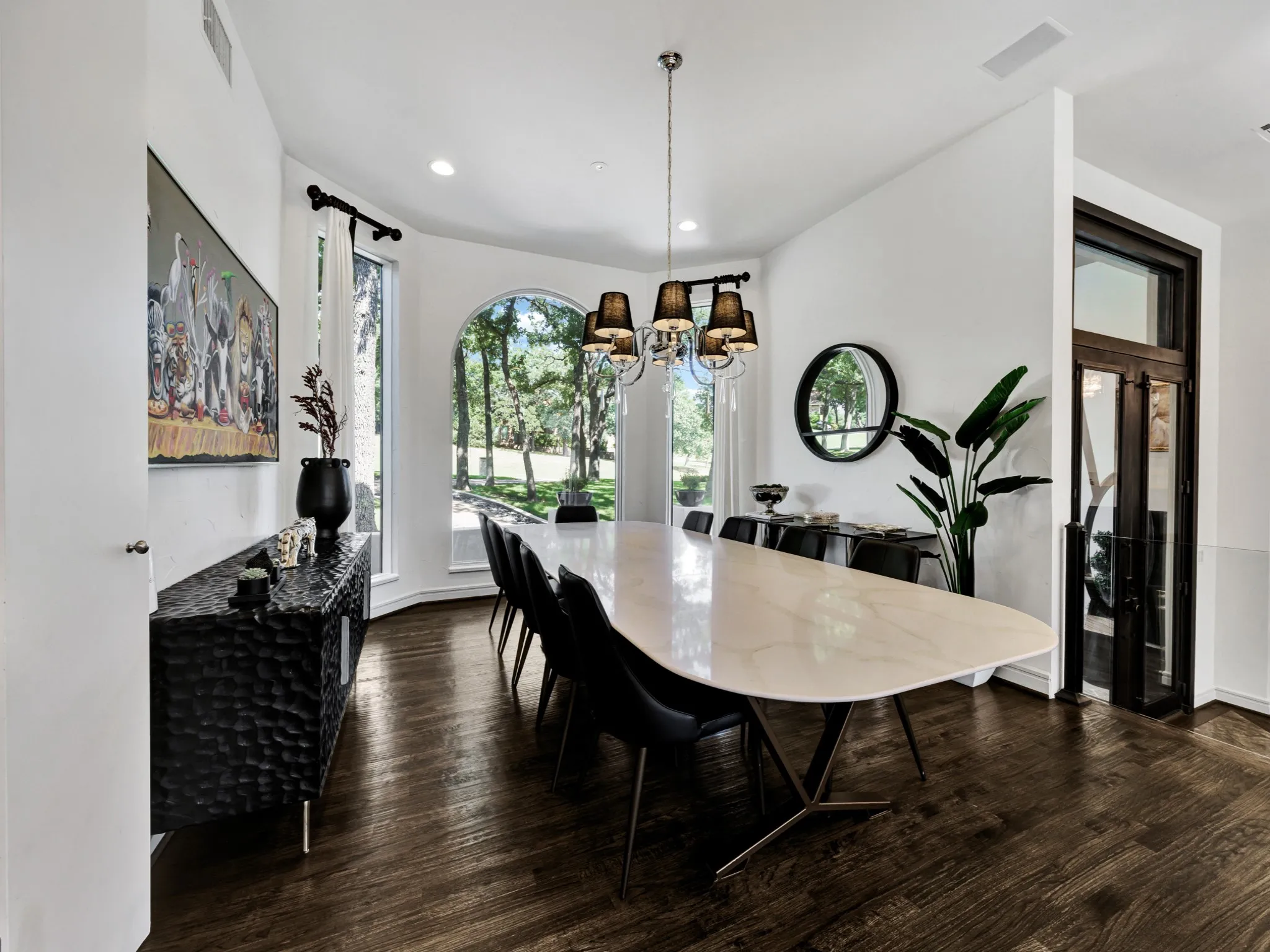 Spacious interior with dark wood-finish flooring, white walls, and a prominent arched window