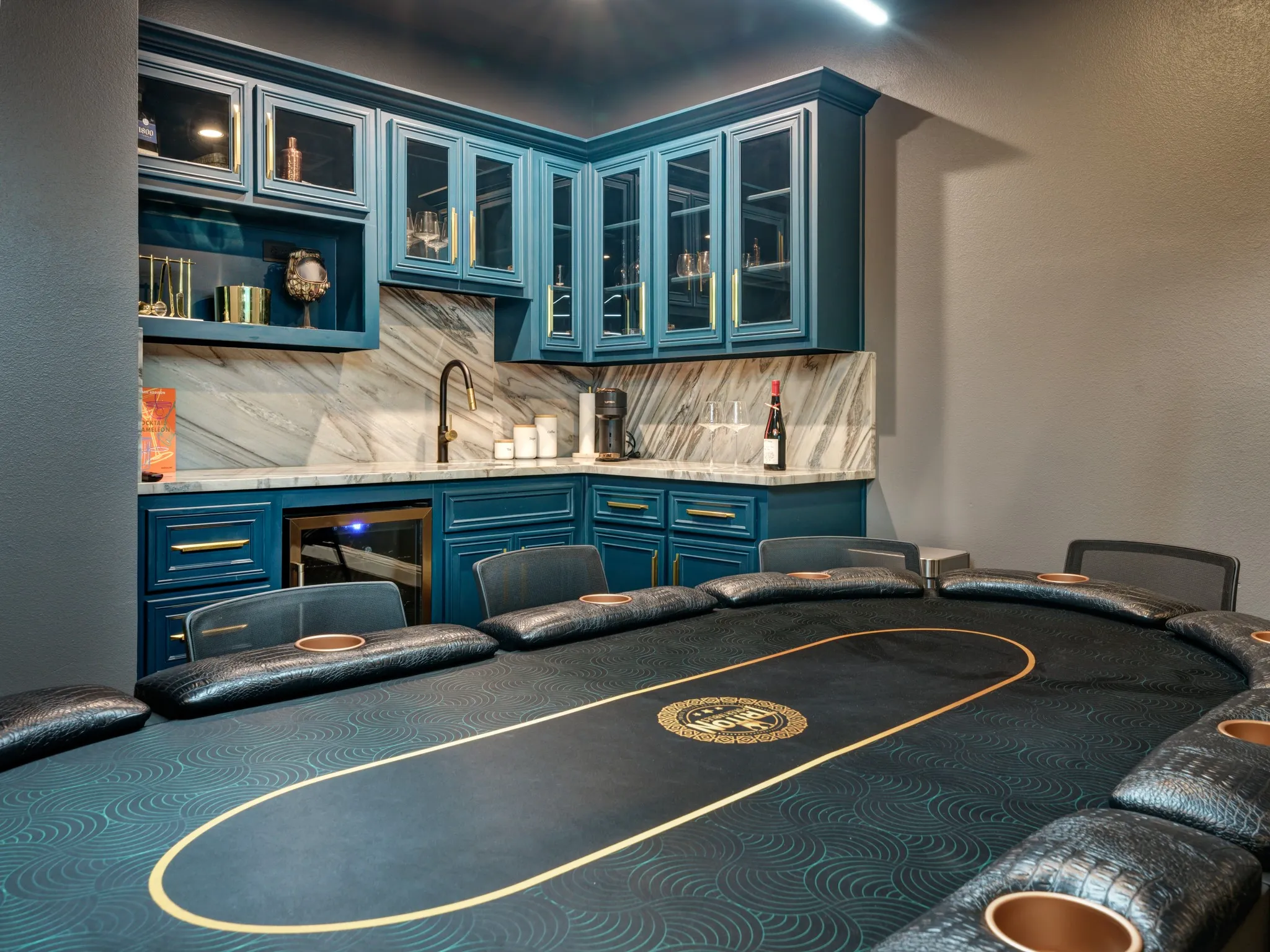 Custom wet bar featuring teal cabinetry, glass-front upper cabinets, and gold-tone hardware