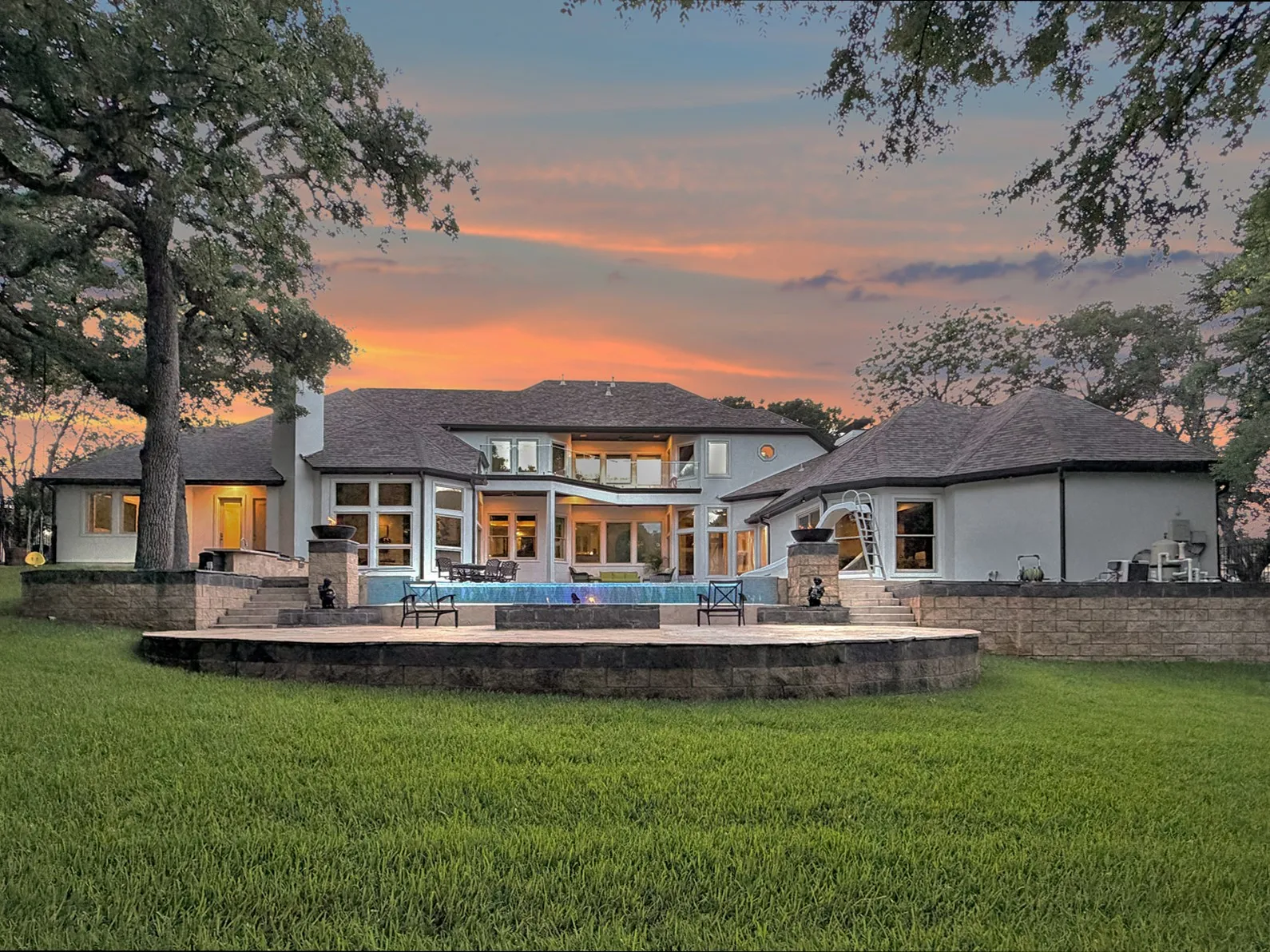 Expansive backyard featuring a multi-level stone retaining wall, a built-in swimming pool, and a dedicated pool house
