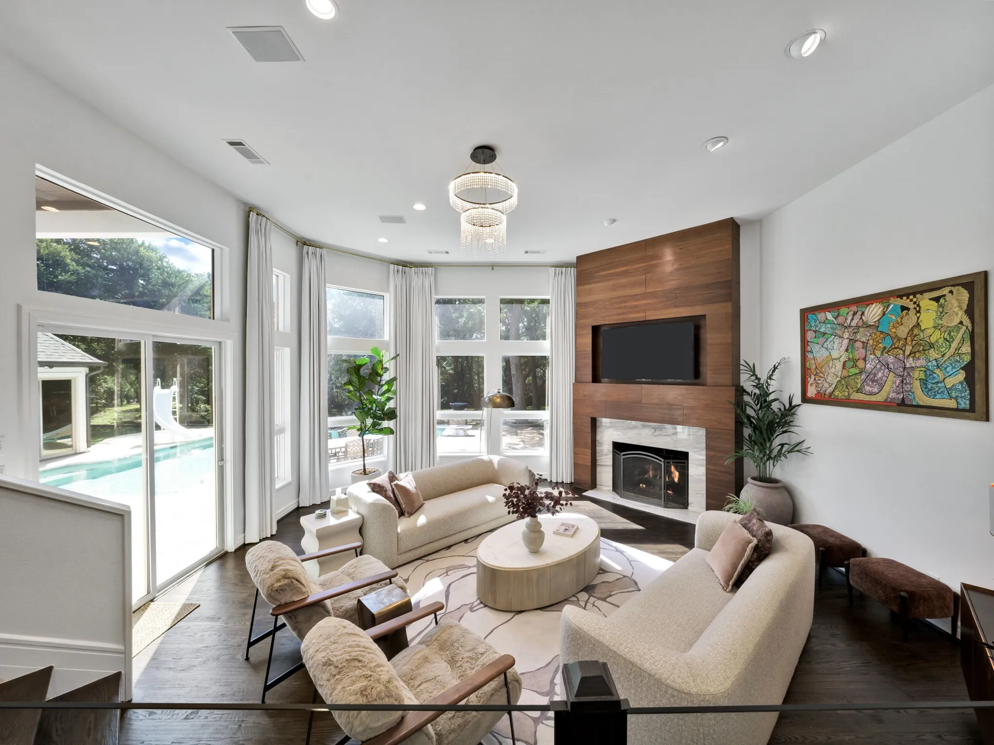 Spacious room featuring dark wood-finish flooring, a wood-paneled fireplace surround with a stone hearth, and extensive window walls