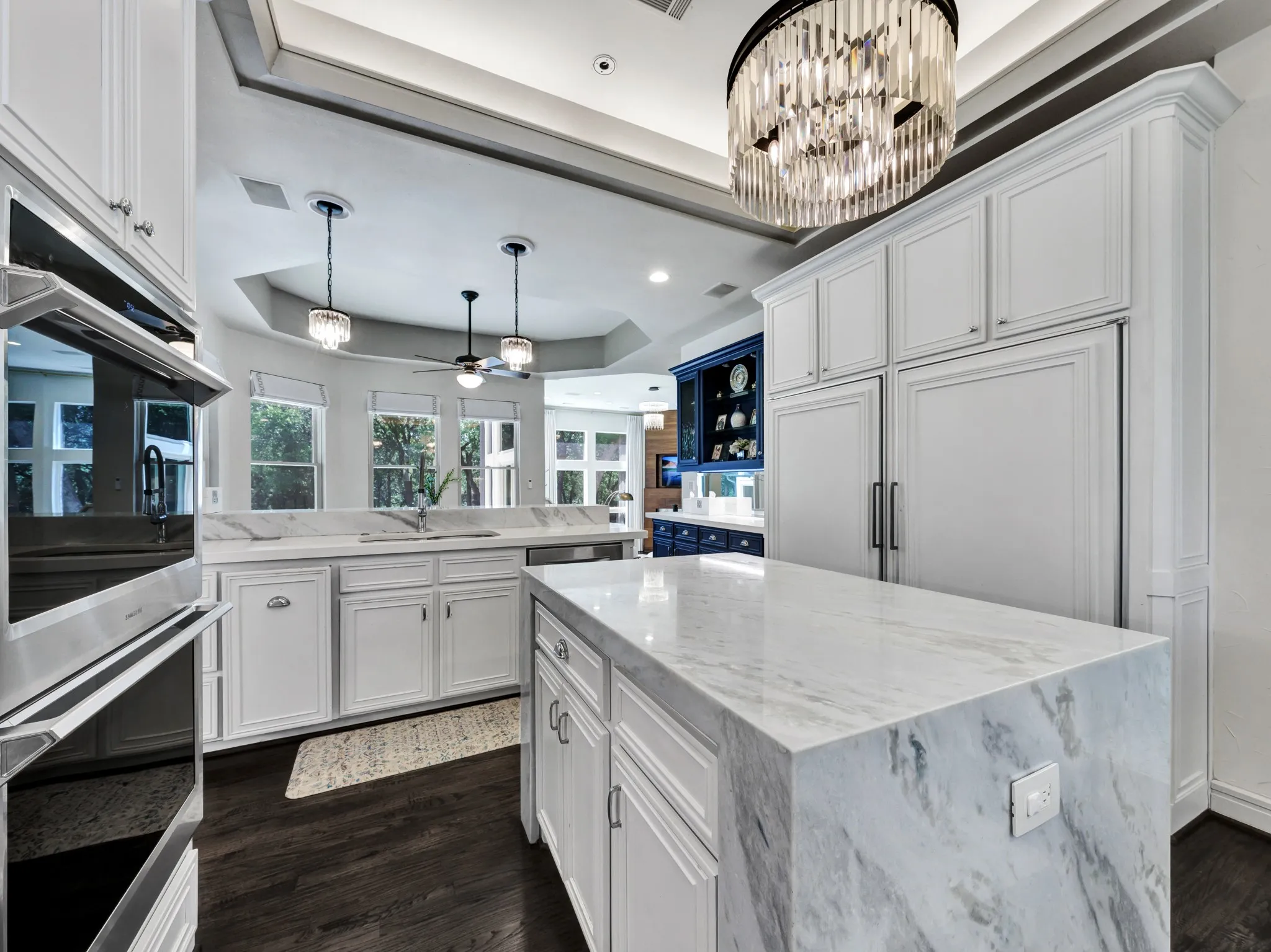 Kitchen featuring a large waterfall island with a stone surface, white cabinetry, dark wood-finish flooring, a built-in oven, and recessed lighting