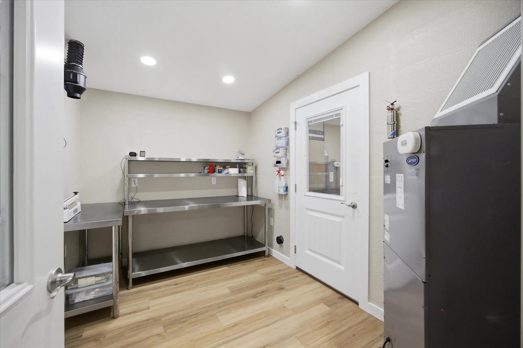 Dedicated prep and packaging room — commercial stainless steel work tables, Carrier HVAC, inline exhaust ventilation, and LVP flooring. Built clean, built right, ready to operate