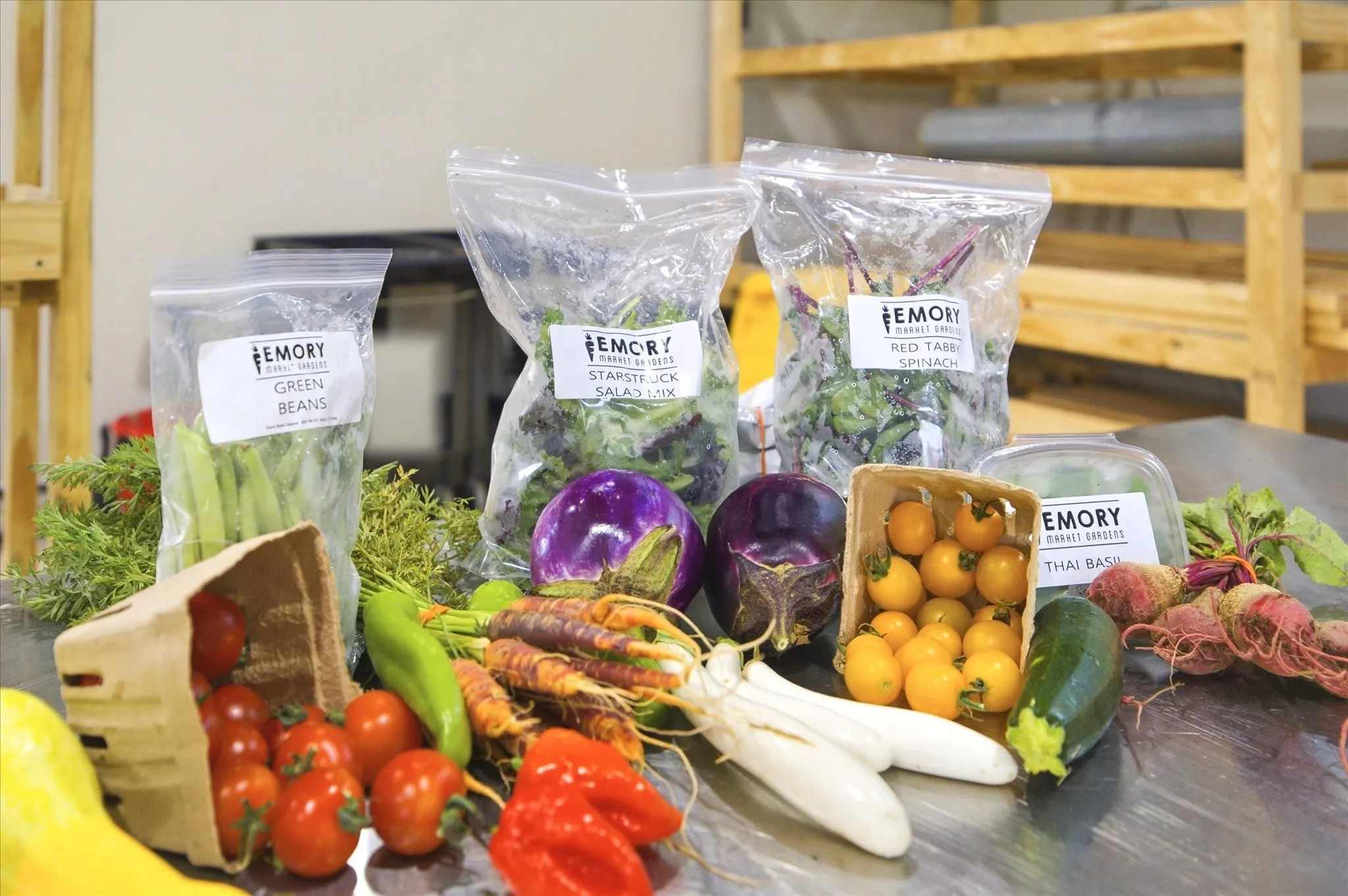 The product line is already built — branded specialty and heirloom produce including Starstruck Salad Mix, Red Tabby Spinach, Thai Basil, and vibrant seasonal varieties. Grown here, packaged here, sold here