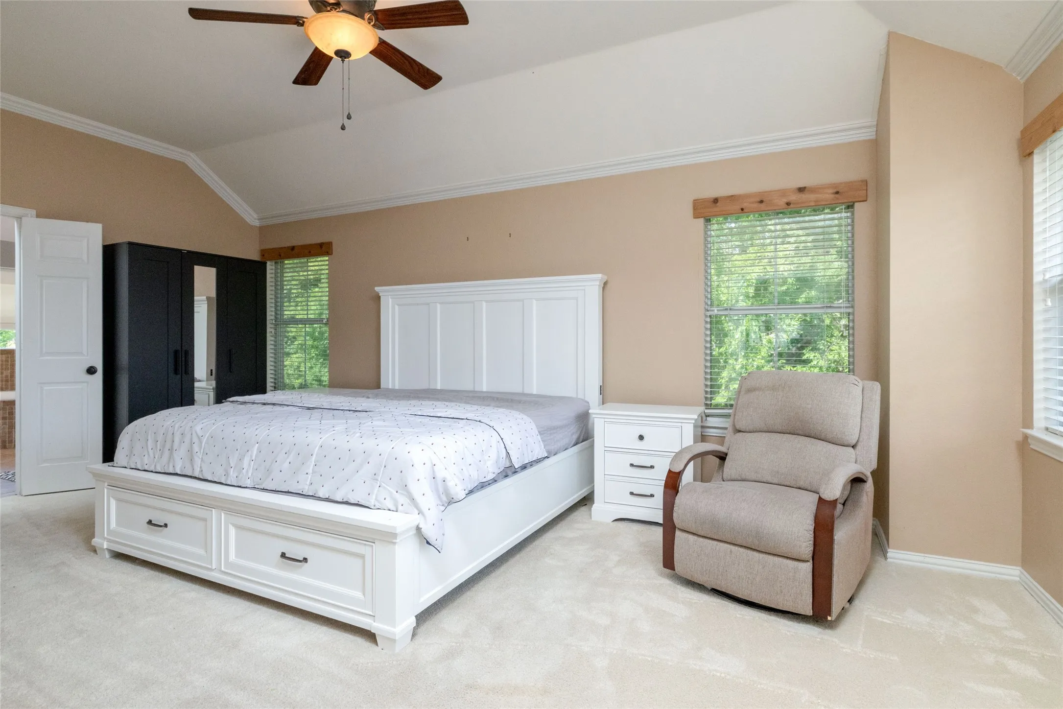 Vaulted ceiling with crown molding, ceiling fan, and two windows with blinds