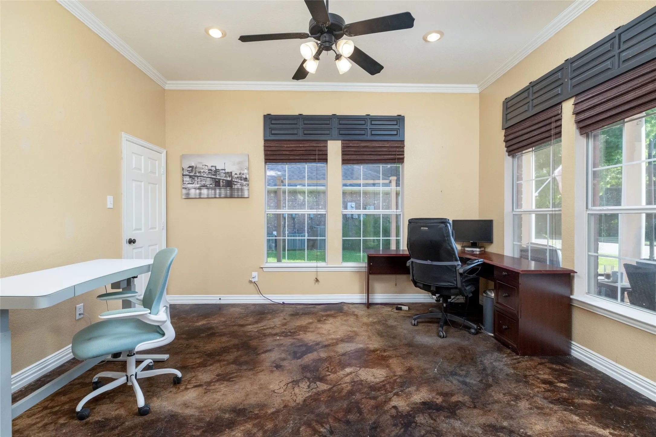 Spacious room featuring rich, textured flooring, multiple windows with decorative valances, recessed lighting, crown molding, and a ceiling fan