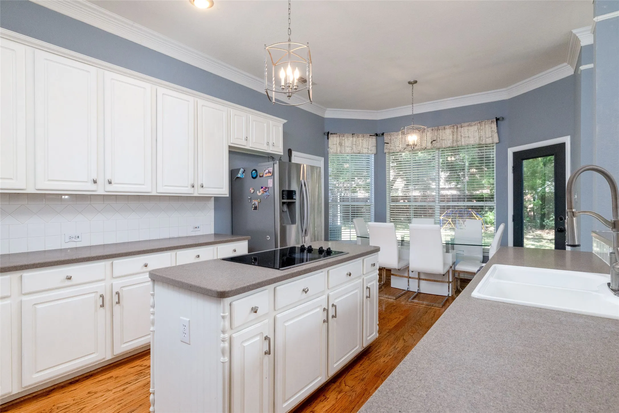 Kitchen featuring white cabinetry, grey countertops, wood-finish flooring, and an island with a built-in cooktop