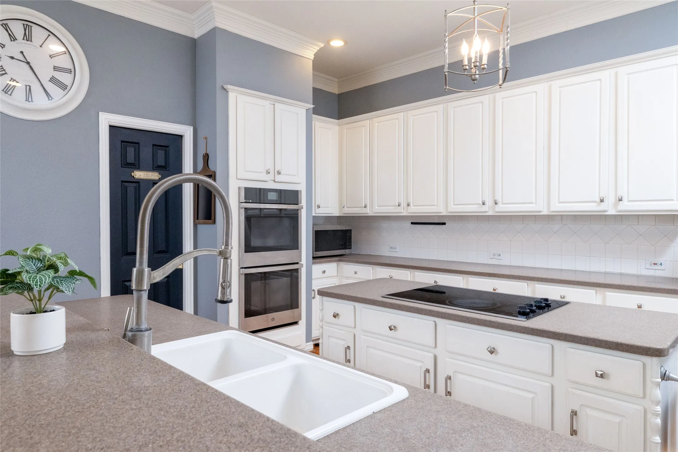 Kitchen featuring extensive white cabinetry, a built-in double oven, and a flush-mounted cooktop