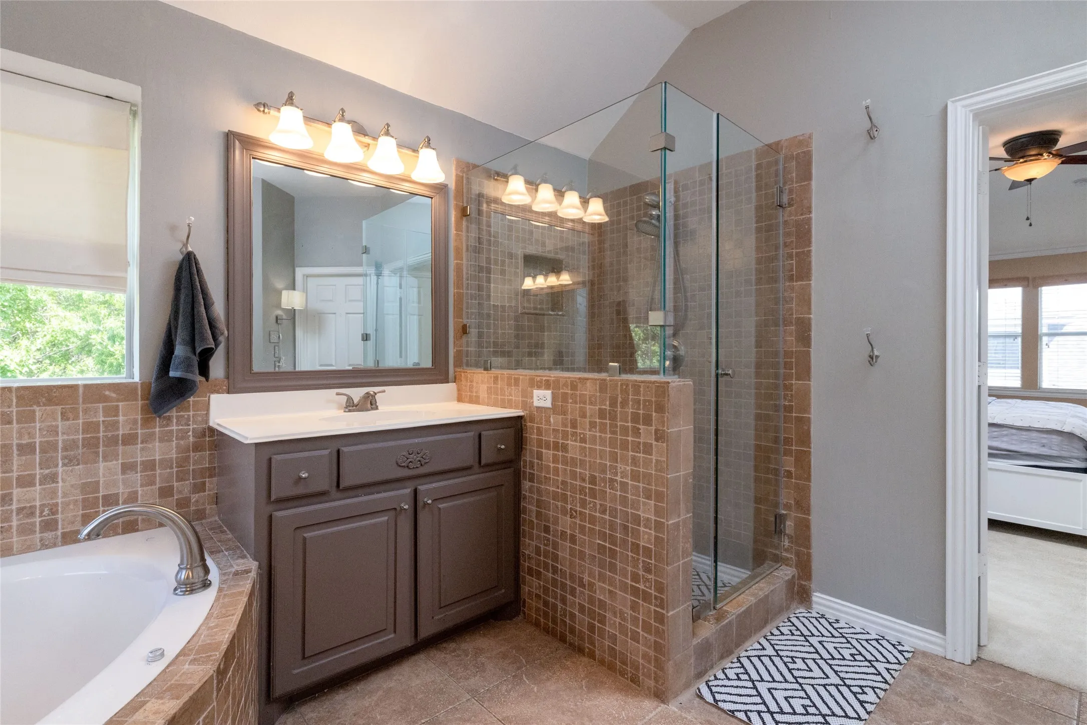 Bathroom featuring a glass-enclosed shower, a built-in jetted tub, a vanity with a white countertop, and tile flooring